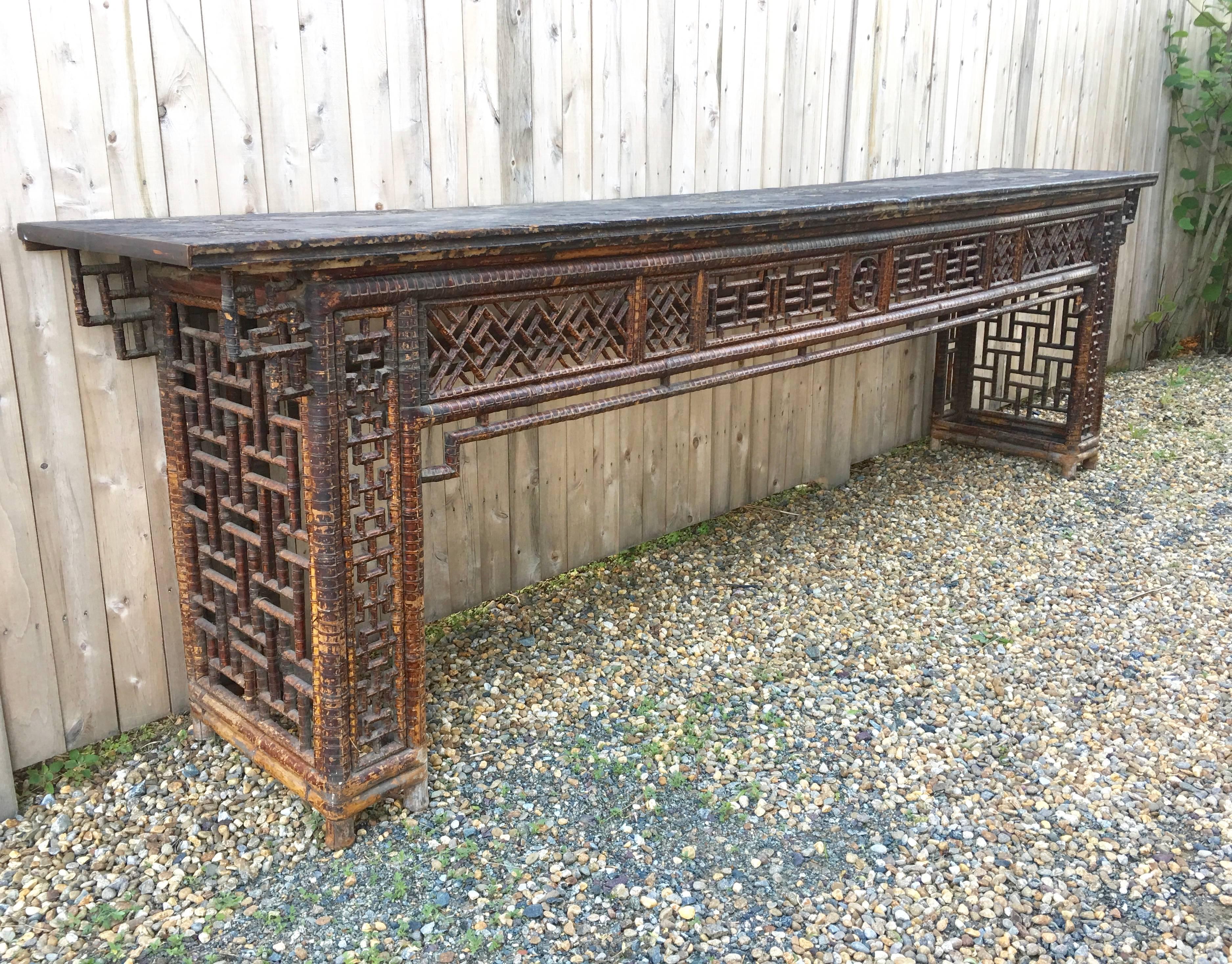An impressive, very long Chinese country table, the distressed, wonderfully patinated black painted rectangular wood top, over geometric bamboo lattice work frieze and legs. We love the character and impressive proportions of this table. It's great
