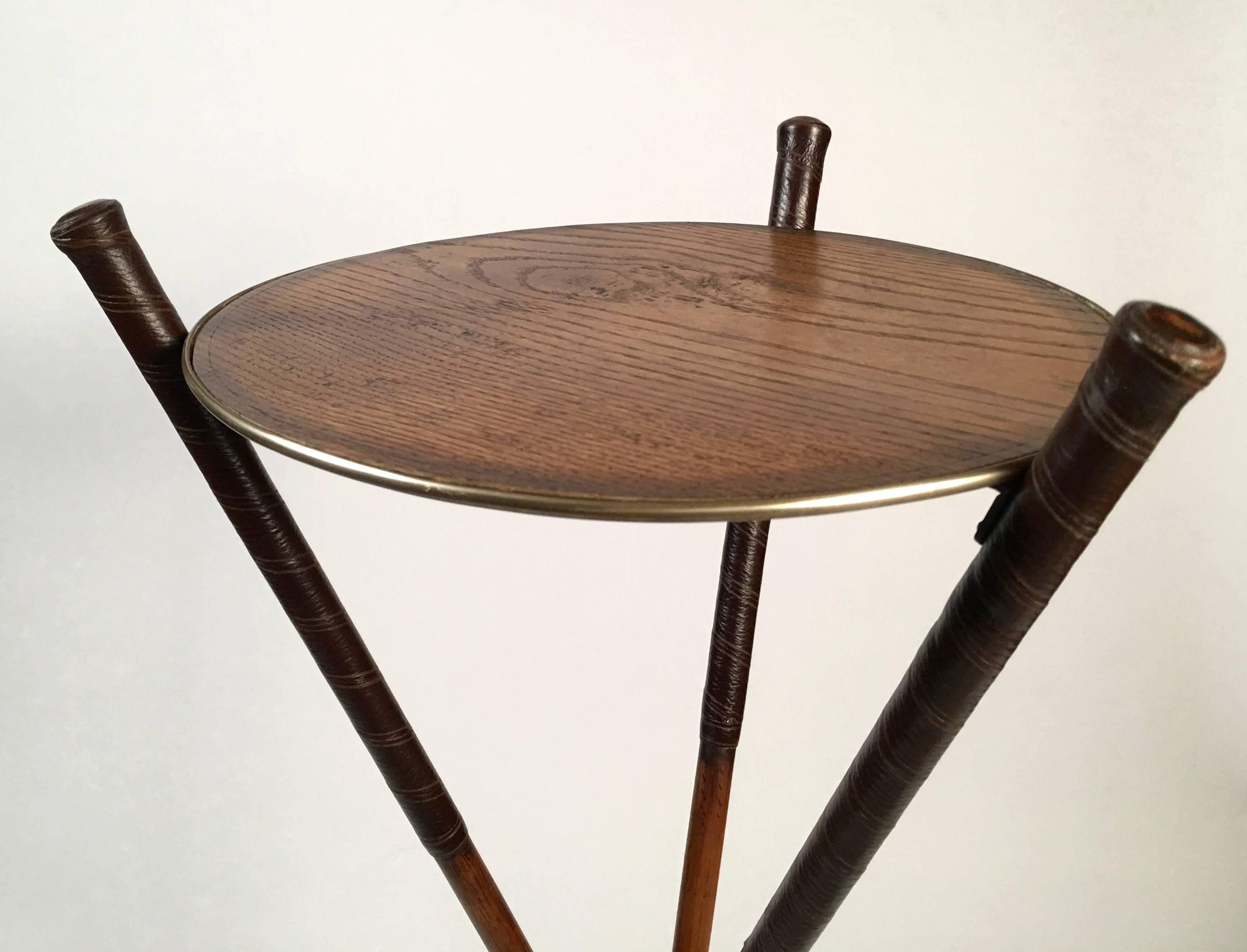 An inventive and well made drinks table made from three vintage Scottish golf clubs, with hardwood shafts, leather wrapped grips and metal club heads (each signed by a different maker), intersecting with decorative metal hardware, the round stained