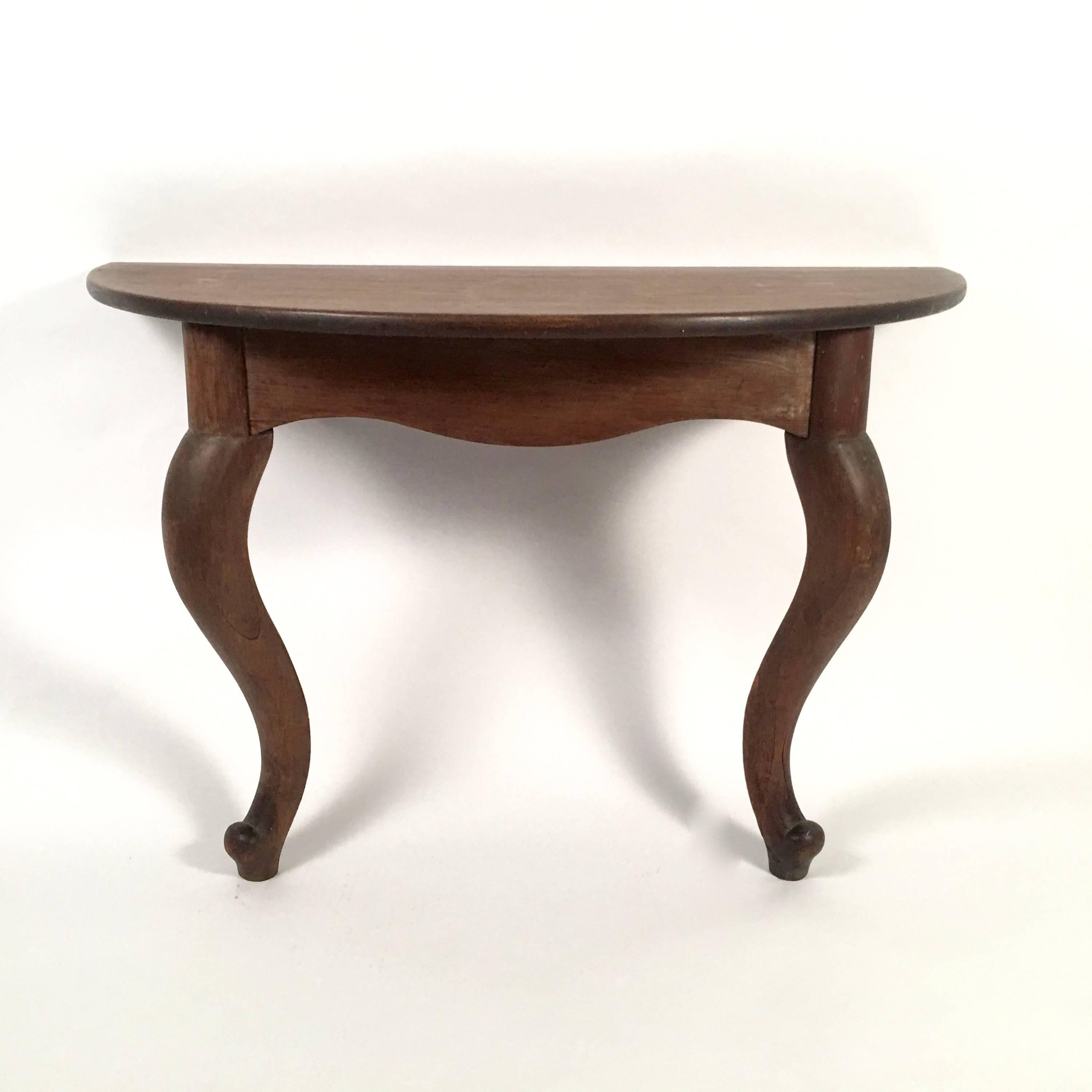 A wonderfully sculptural pair of solid walnut console tables, the semi circular tops supported by cabriole legs, American, circa 1840. These tableS have great presence and retain a beautiful old, dry finish. In their simplicity and boldness, they