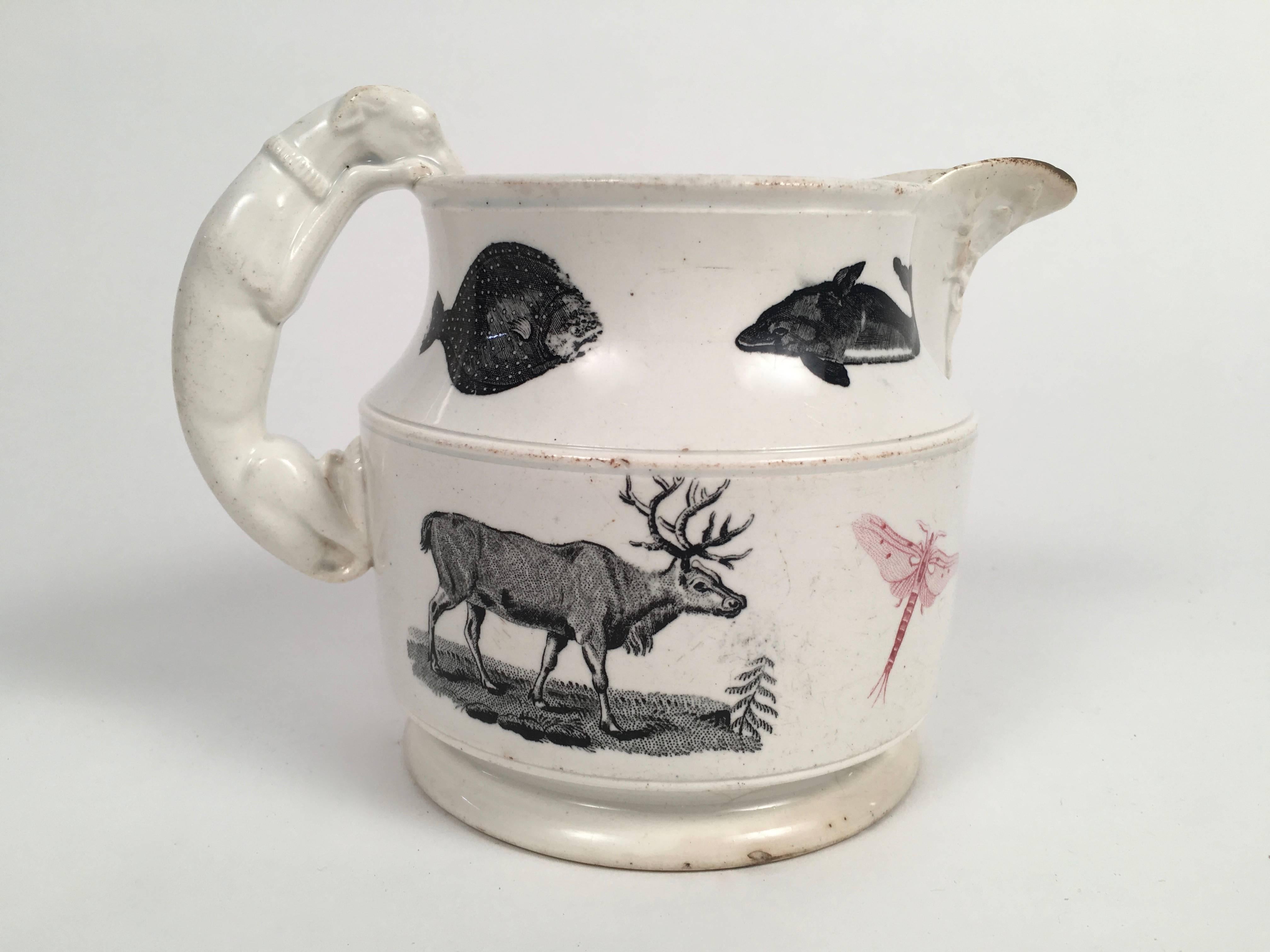 An unusual and charming Staffordshire Menageries pattern pottery milk pitcher, the white ground pottery with a hound-form handle and a stag embossed on the exterior of the spout, decorated overall with a wide variety of black and pink transfer