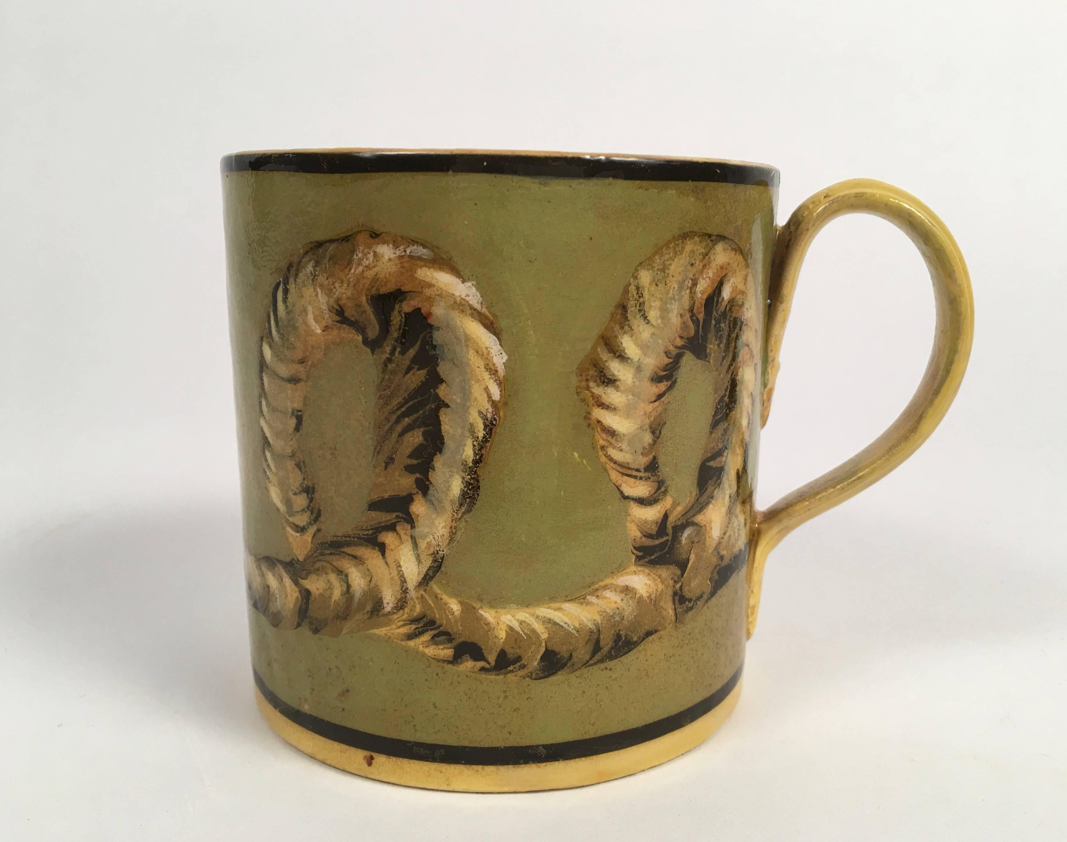 A French mochaware pottery mug in yellow with three dimensional looking rope twist decoration, or décor de cordages, in yellow, brown and white on a sage green ground with applied strap handle by Creil, circa 1830. Generously proportioned with