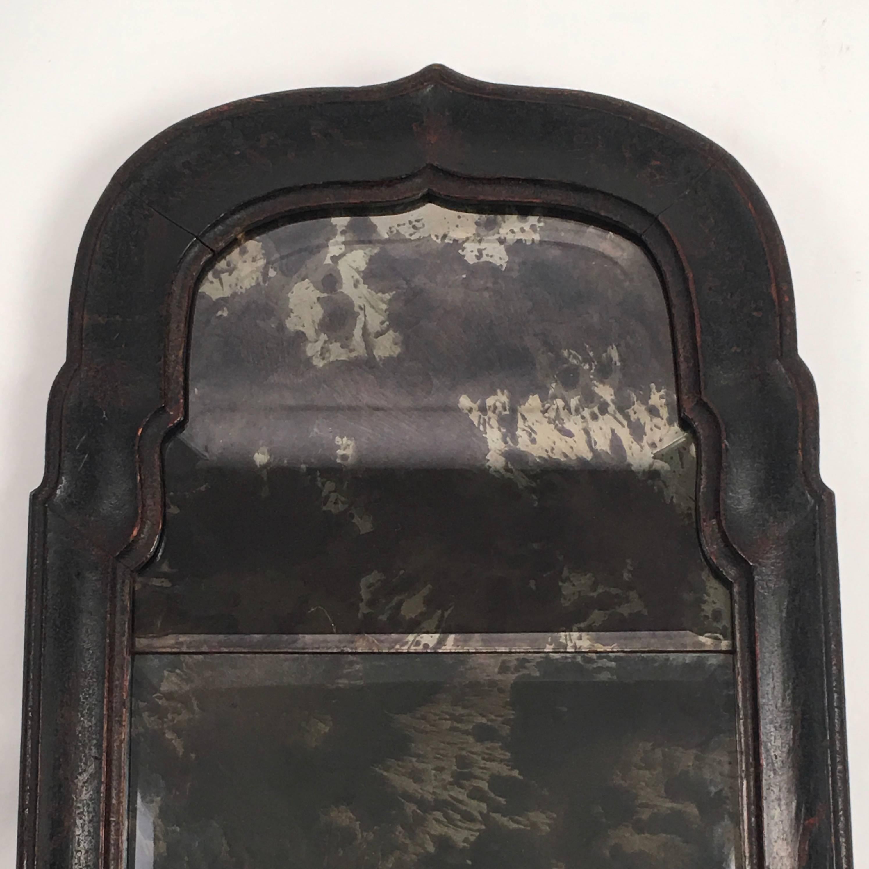 An early Queen Anne period black japanned, or lacquered, chinoiserie decorated mirror, the bracketed arched top over a rectangular lower half, the frame with wonderful bold form and old leathery patina, retaining traces of its original gold painted