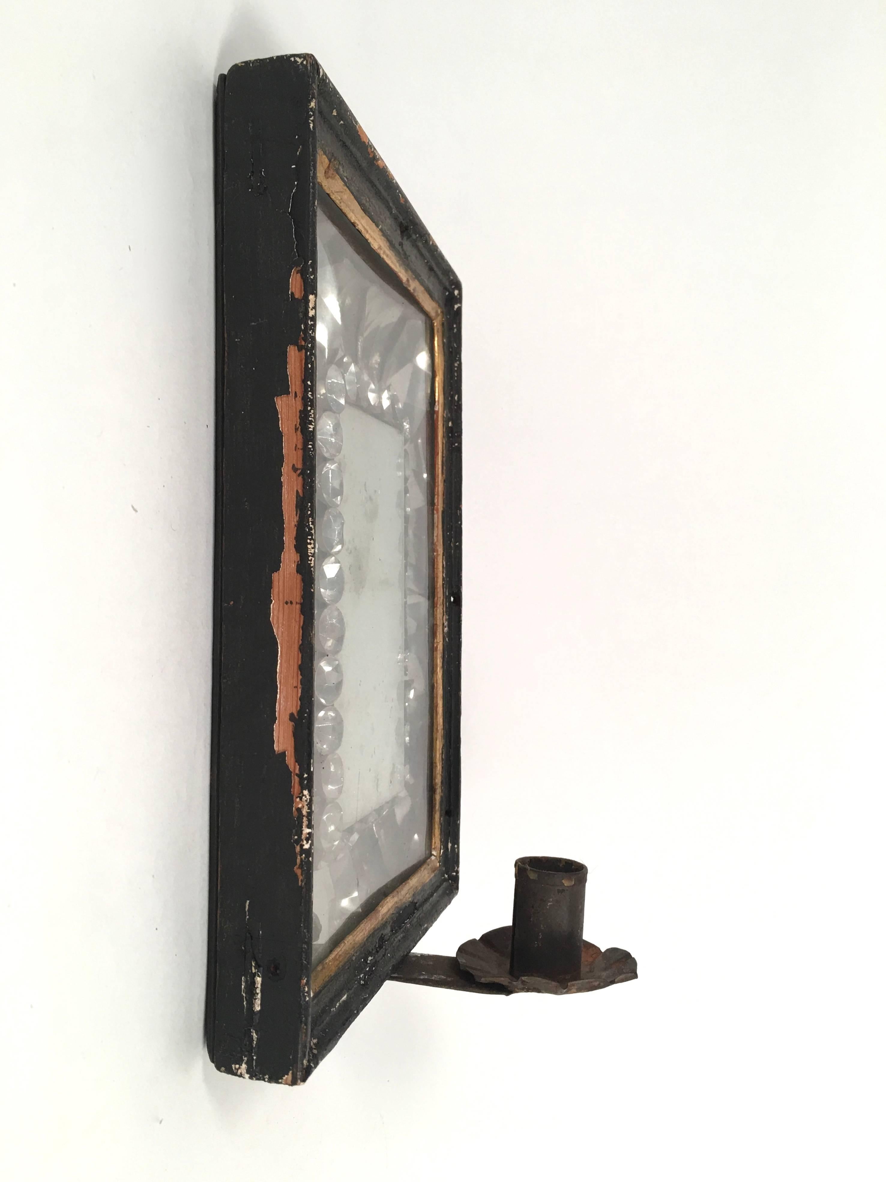 A striking, early American mirrored wall sconce, the ebonized wood frame, with gilded interior fillet, surrounding a beautifully complex arrangement of crimped and formed tin, designed to resemble faceted crystals, surrounding an early rectangular