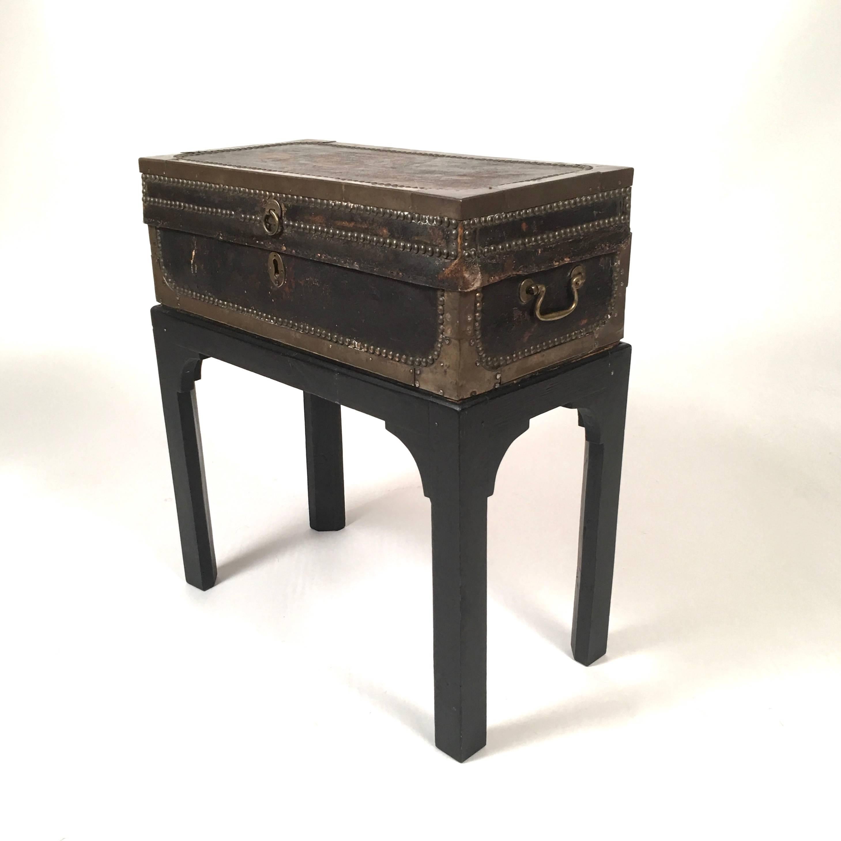 A 19th century leather bound brass stud decorated and mounted wooden sea captain's chest, mounted on a later black painted Chippendale style stand, perfect for a side table next to a chair or sofa. Wonderful small size and patina.

Dimensions on