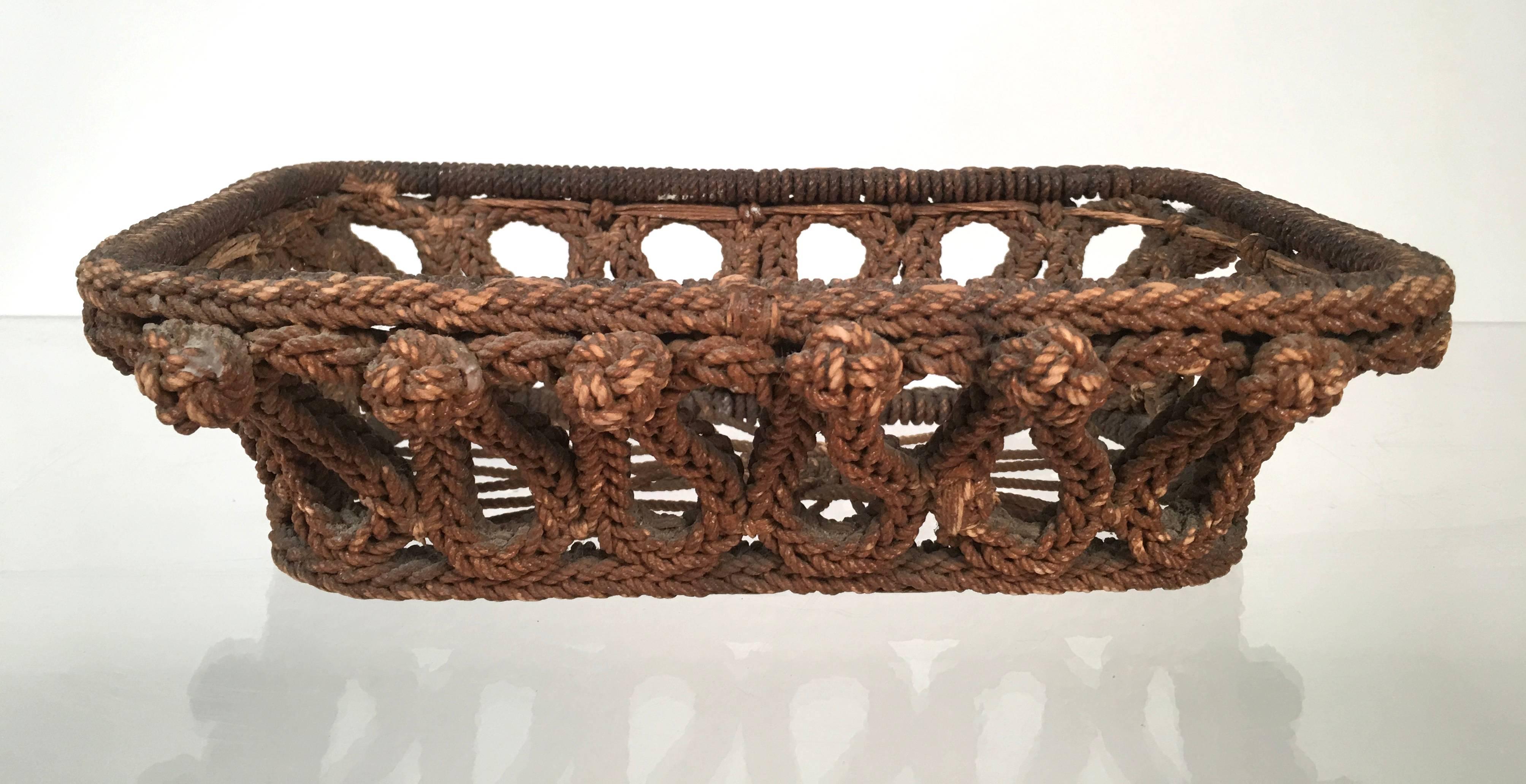 A  19th century sailor-made rope work basket with intricately knotted sides and openwork bottom. From sea chest handles, or beckets, to flask covers, balls and knife covers, sailors would use whatever extra cordage was available to make items both