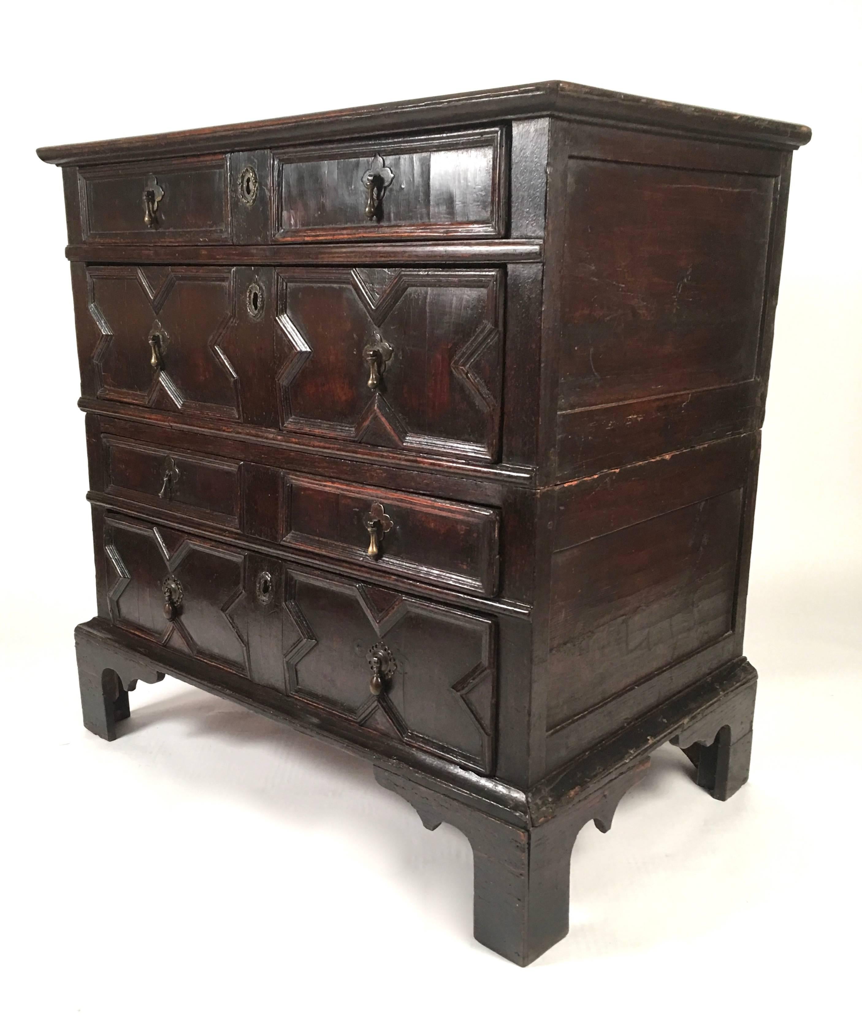 A Charles II carved oak chest of drawers, the rectangular top above four drawers in graduated sizes, with carved geometric moldings and brass drop drawer pulls, on later bracket feet, with English, 17th century. 
This chest of drawers comes apart in
