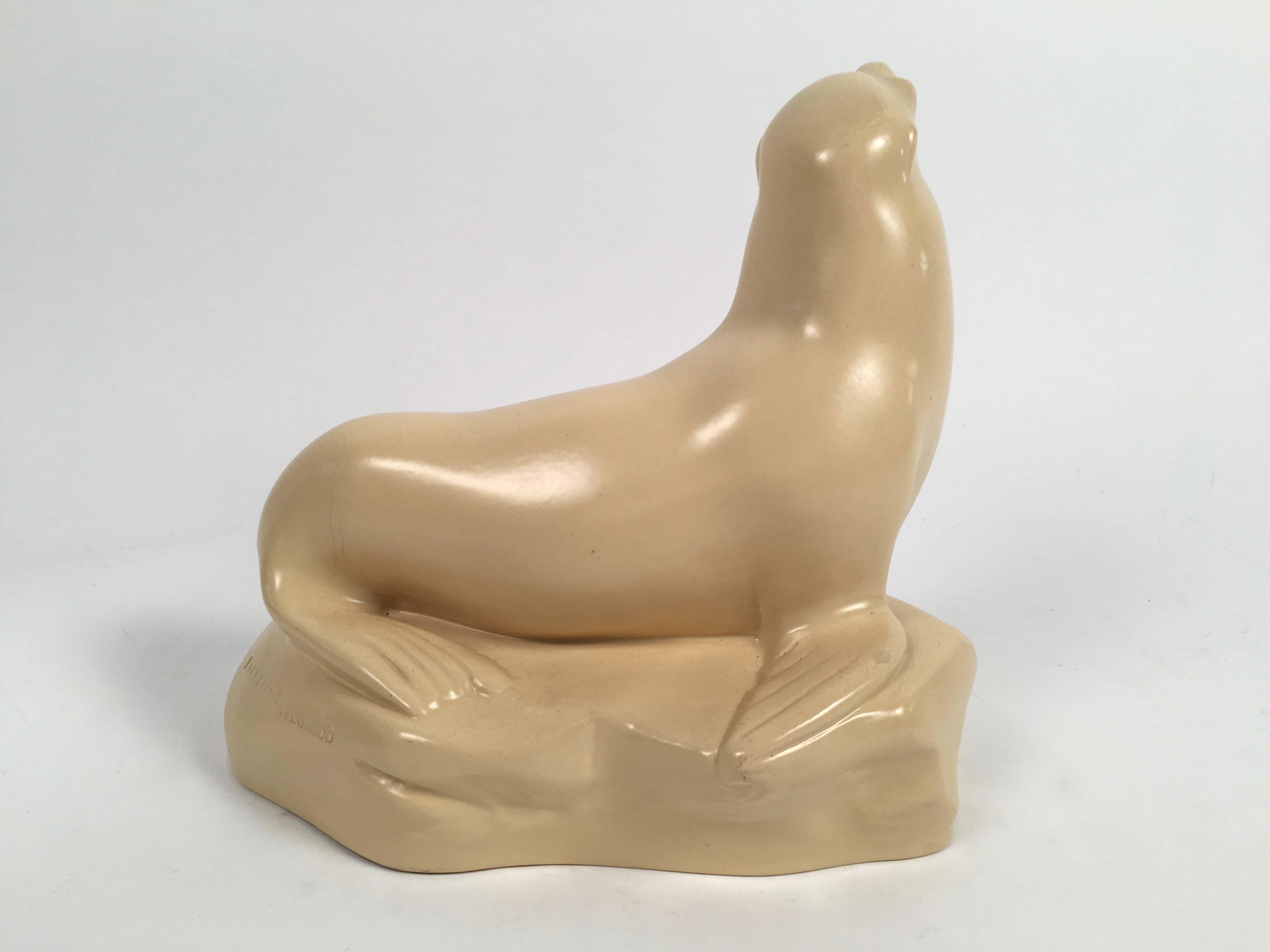 A Wedgwood pottery sculpture of a sea lion, or seal, with a matte straw glaze, beautifully modeled by John Skeaping in 1927 and made by Wedgwood and Sons, Barlaston, England, circa 1935. Signed with impressed signature and marks on back of base.