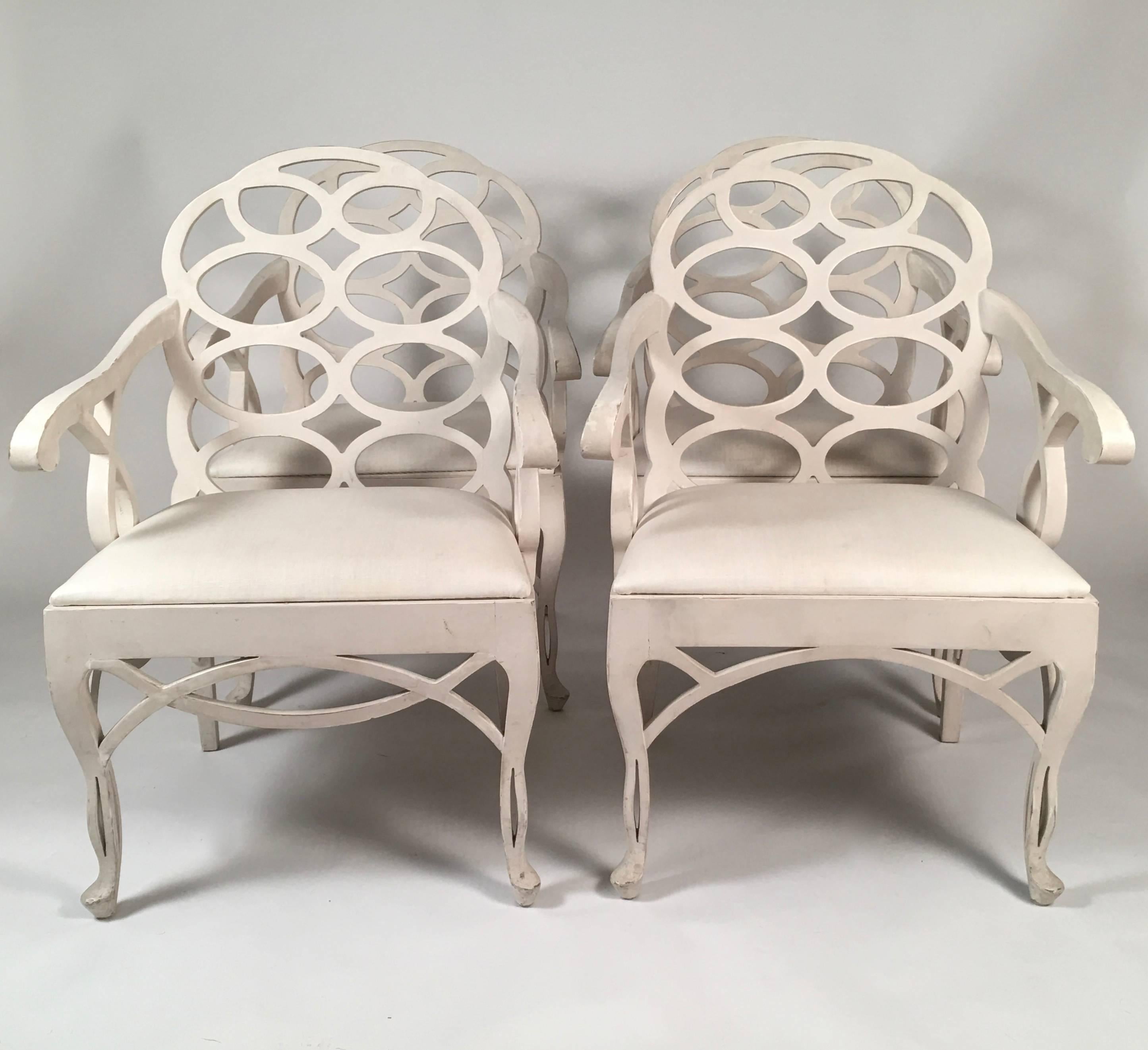 A set of four generously proportioned Loop armchairs, by iconic designer Frances Elkins (1883-1953), in cream lacquered wood, the backs with wonderfully graphic oval latticework design , with down swept arms, with loop supports, over an upholstered