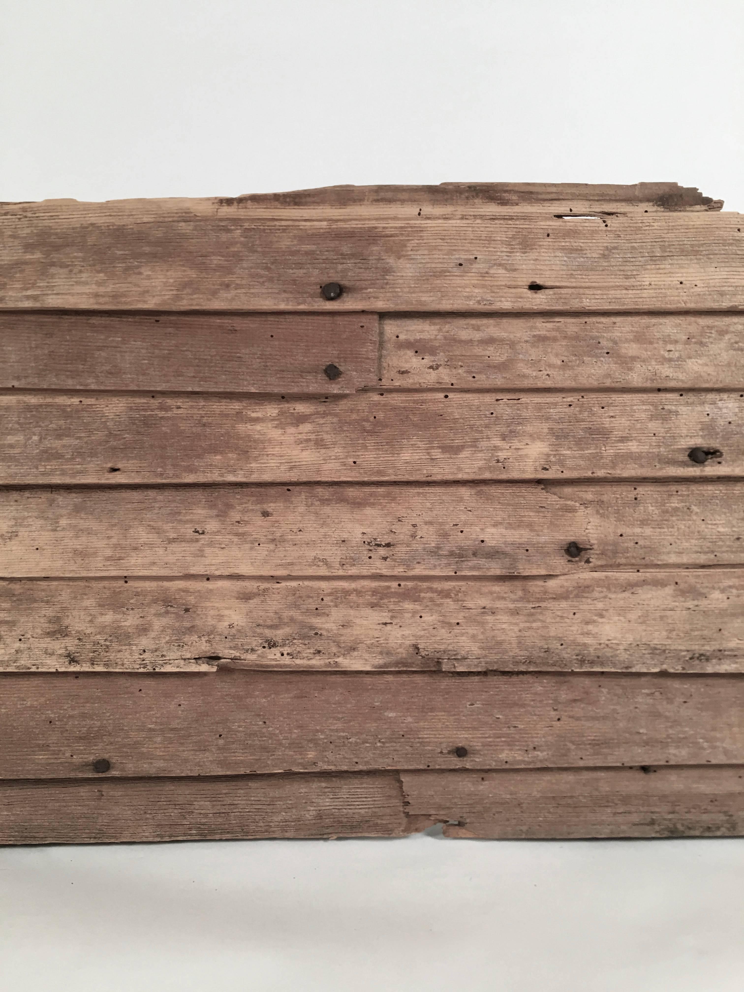 A fragment of 18th century wood clapboard siding with hand cut nails, the rectangular overlapping boards with wonderful age and patina, from a Hampton New Hampshire farm house, circa 1725. The square cut-out hole wold have been for an old pipe or