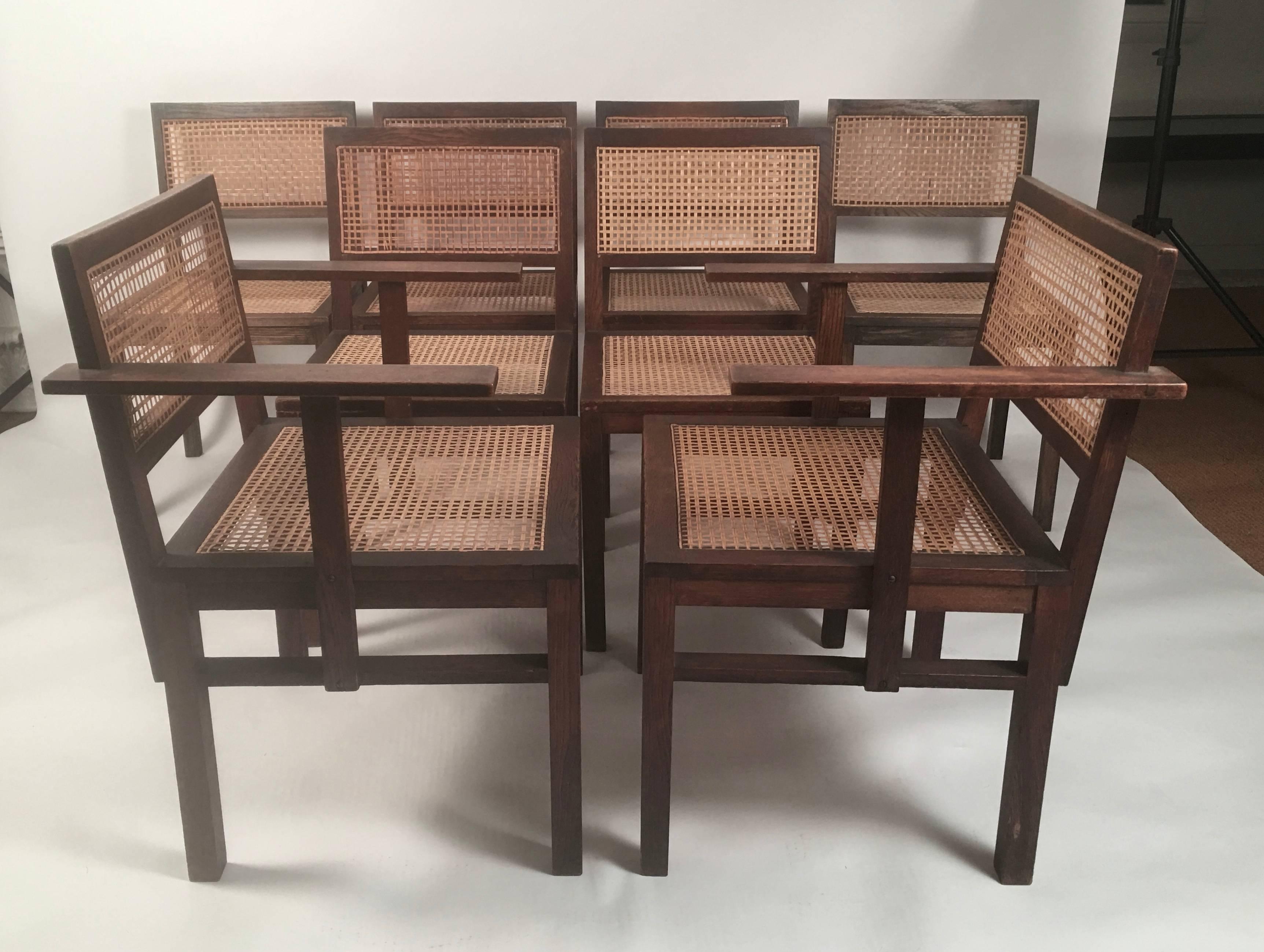 A set of 8 German Bauhaus period dining chairs in oak with rectangular caned backs and seats, comprising two arm chairs and six side chairs. Suede seat cushions included, if desired. The cushions are used and show signs of wear, but may be cleaned