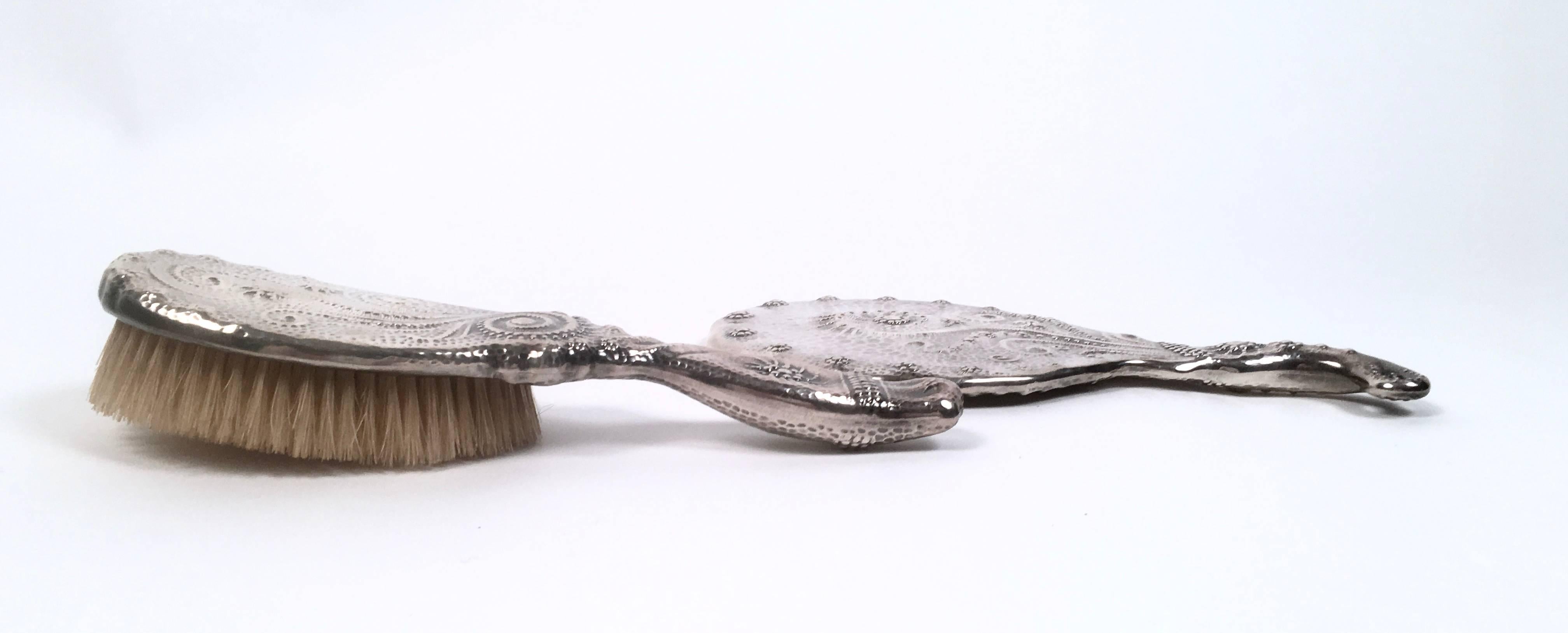 A fine quality 19th century aesthetic movement period sterling silver hand mirror and hair brush, American, circa 1875, with unusual and 'modern' hammered and raised decoration, inspired by Japanese design, featuring abstract swirl and star