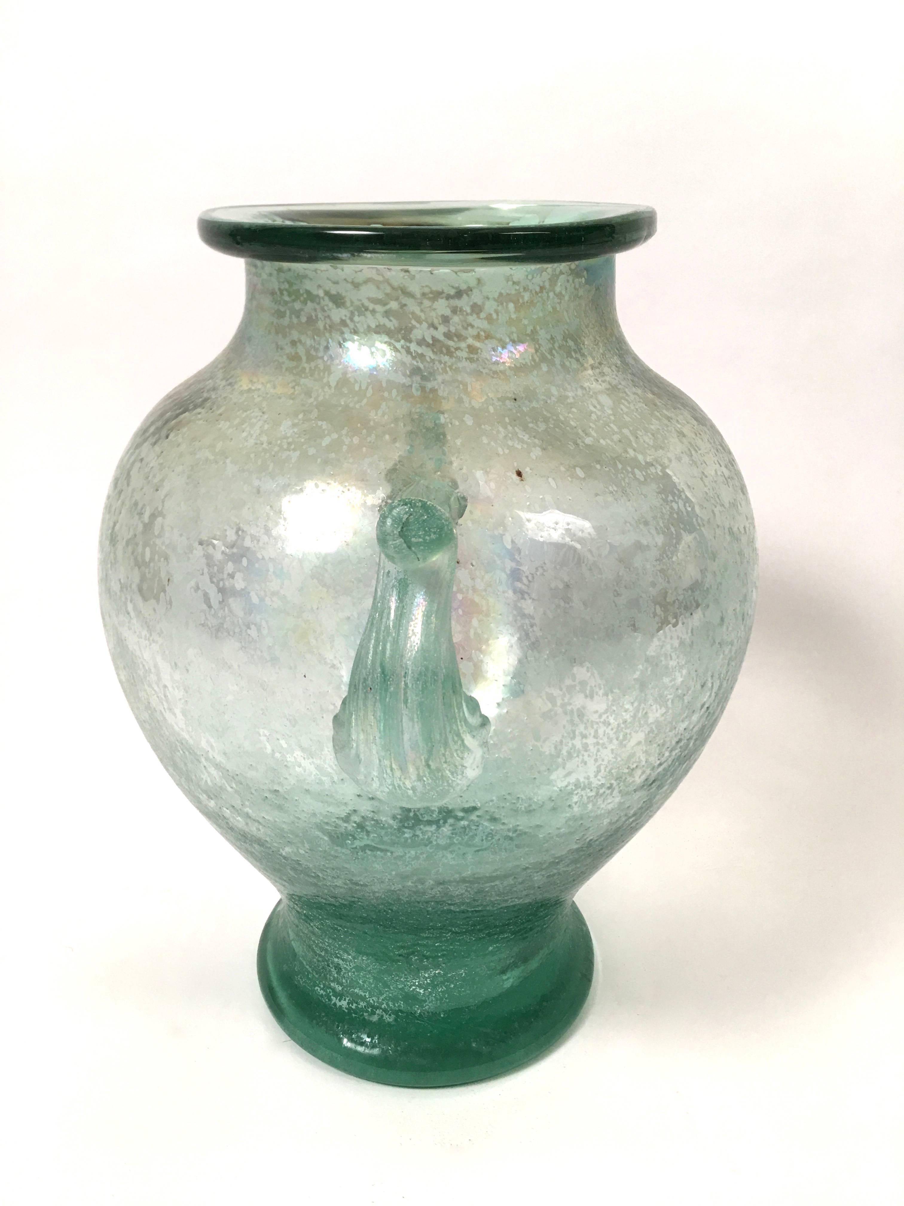 A large Murano Neoclassical  green glass vase of ovoid shape with everted rim and applied handles, in the Scavo technique, which resembles the surface of Ancient Roman glass with its textured and frosted surface.