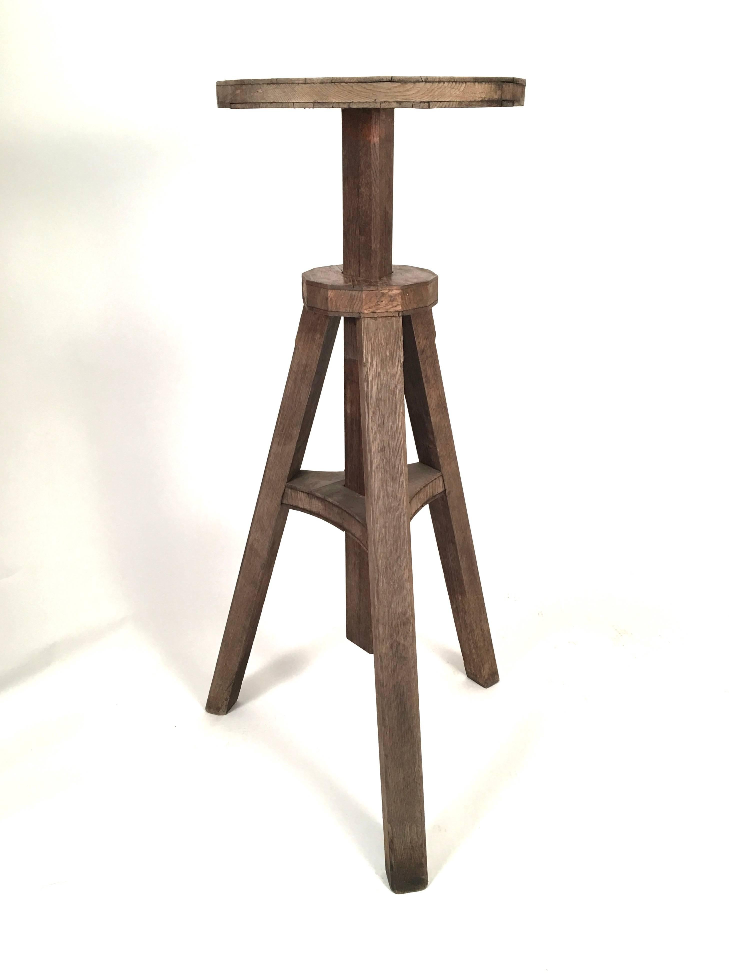 A hard to find sculptor's stand in oak,  circa 1900, the circular rotating platform over an  adjustable height support on 3 chamfered square section legs joined by a triangular plinth with carved wood crank to set the desired height. Very solid and