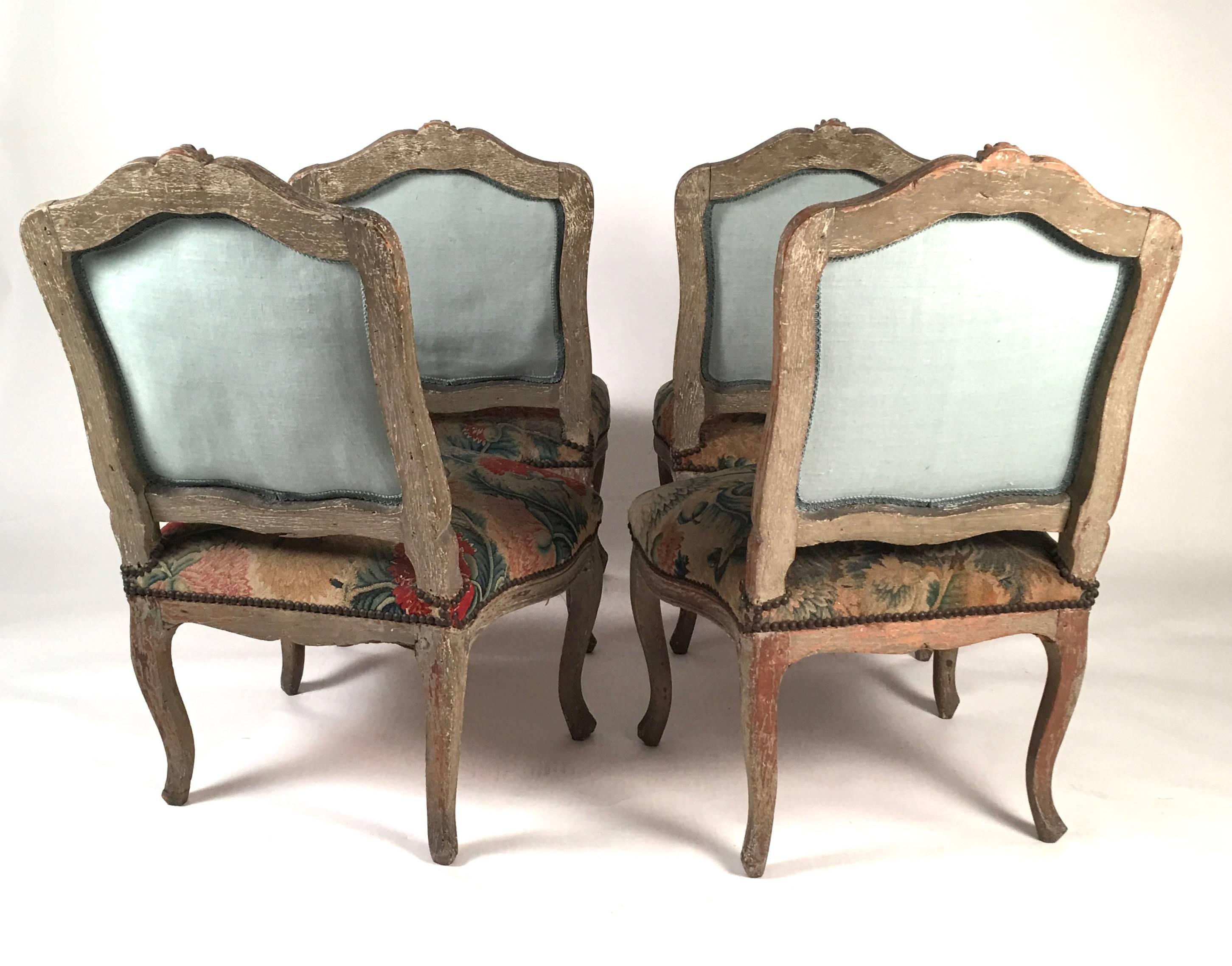 A set of 4 18th century  French Louis XV chairs, upholstered with period floral needlework, with grey painted frames, the arched backs and serpentine seat rails with carved floral decoration, on cabriole legs.  The floral needlework is wonderfully