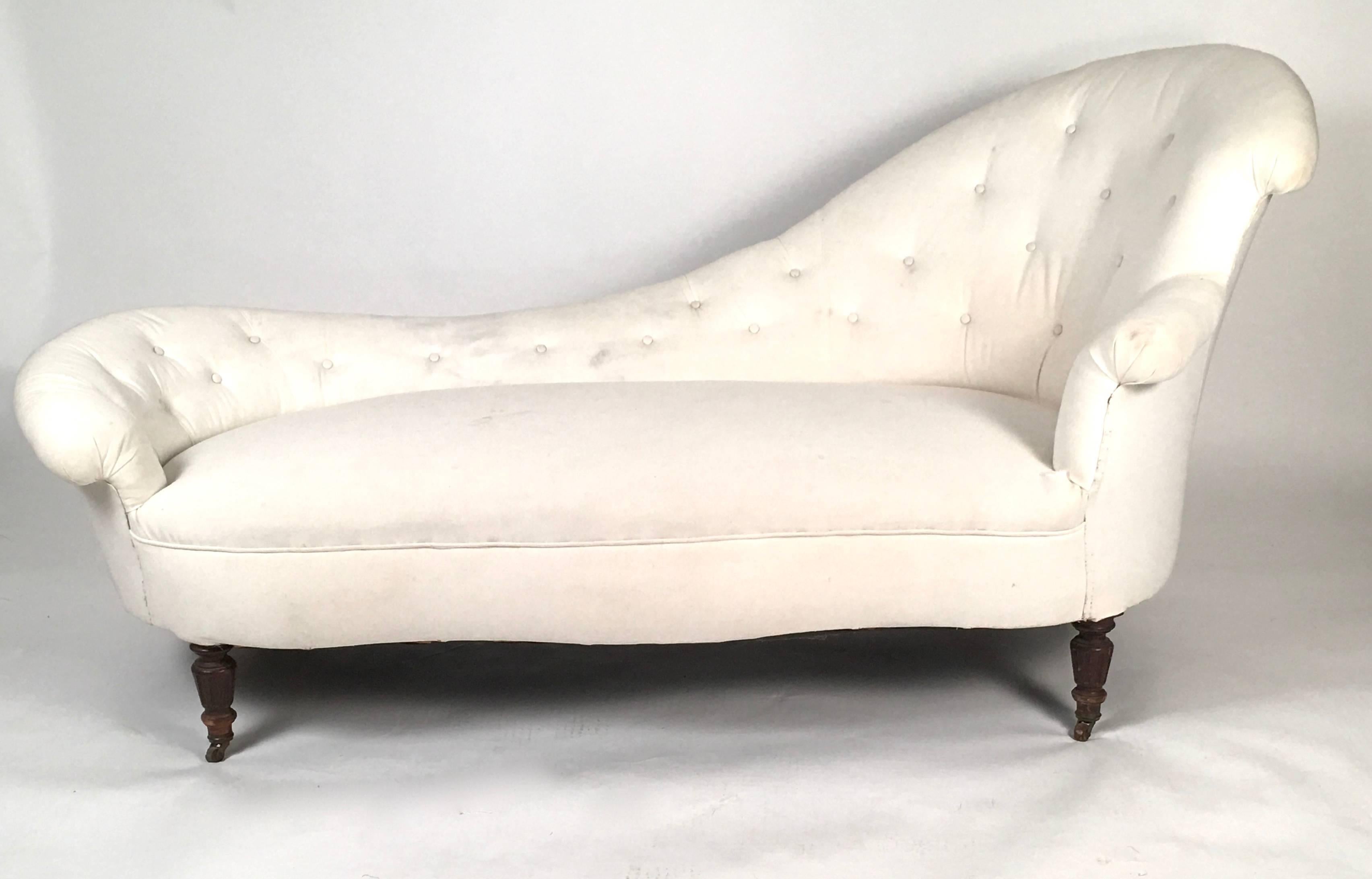 A large, comfortable and stylish Victorian chaise long, with beautifully curved back and sides and tufted back, on carved, fluted tapering legs. Currently in older white duck cloth, ready to be reupholstered in the fabric of your choice. 