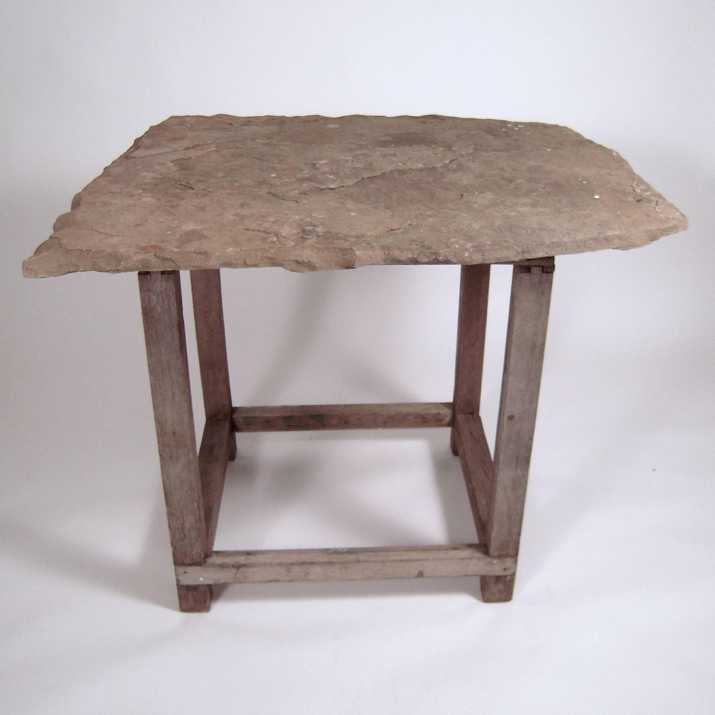 A table made from a massive, English roof slate tile top, mounted on a square section weathered oak base, the legs joined by cross stretchers. The tile is in its original form, with a small hole which was used when it functioned as a roof tile. The