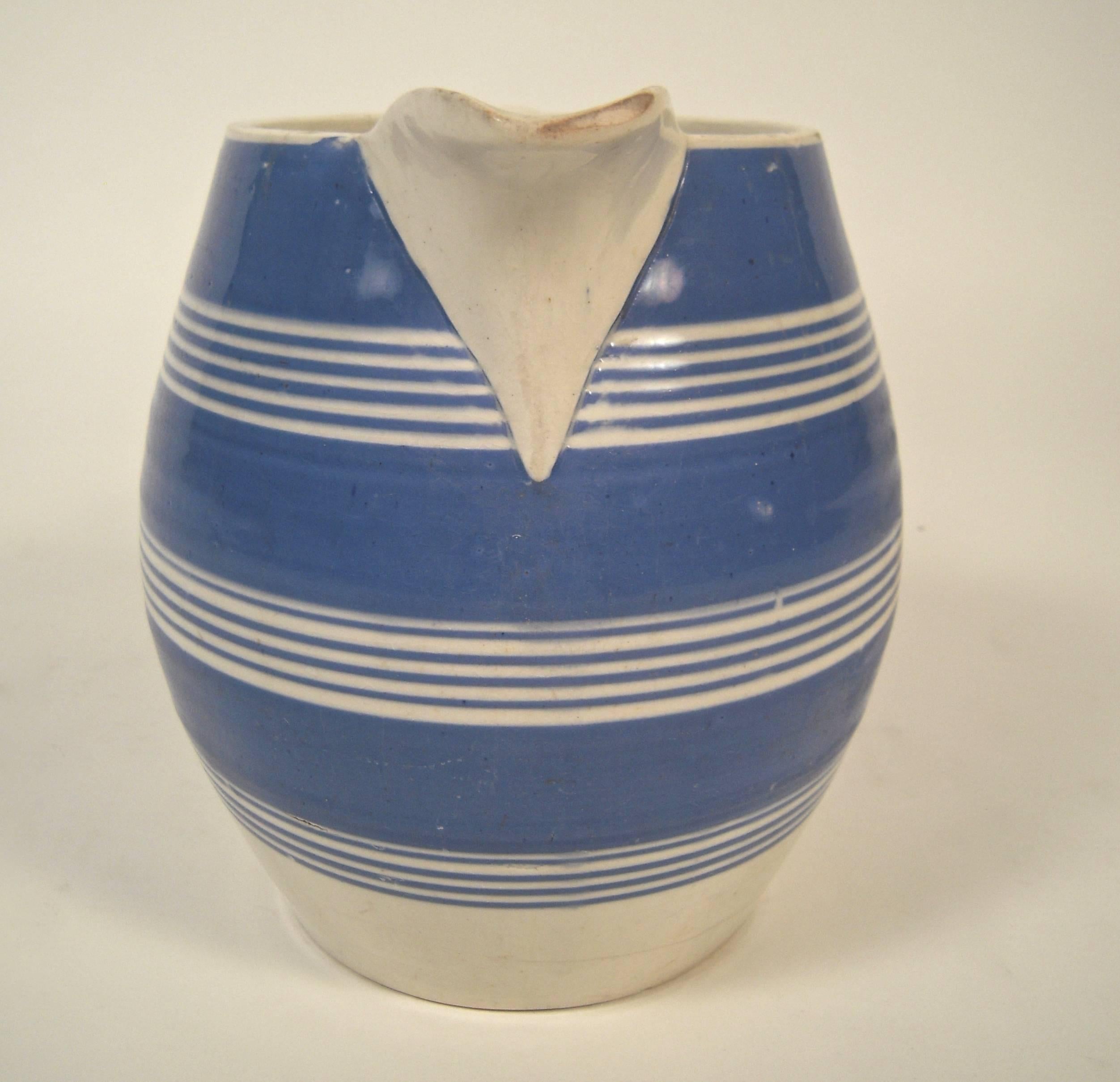A beautiful, large mochaware barrel form pitcher, decorated with blue and white stripes of alternating thickness, Staffordshire, England, circa 1870-80.