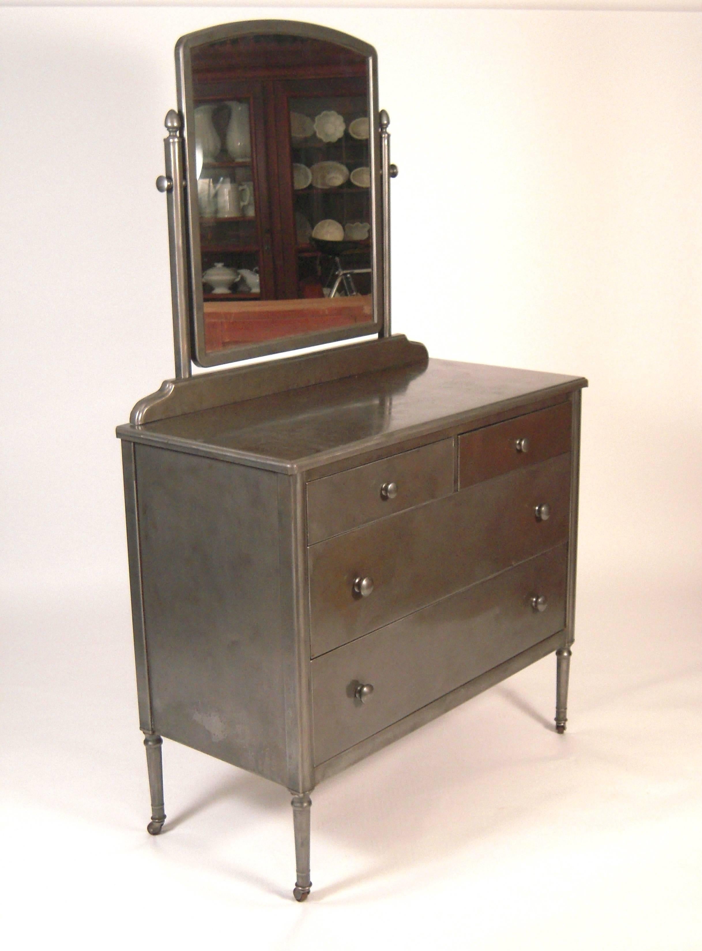A waxed steel Sheraton style dresser, with good patina, the adjustable swivel mirror, over the chest of drawers which has two short drawers over two long drawers, raised on inverted tapering cylindrical left with casters, American, circa