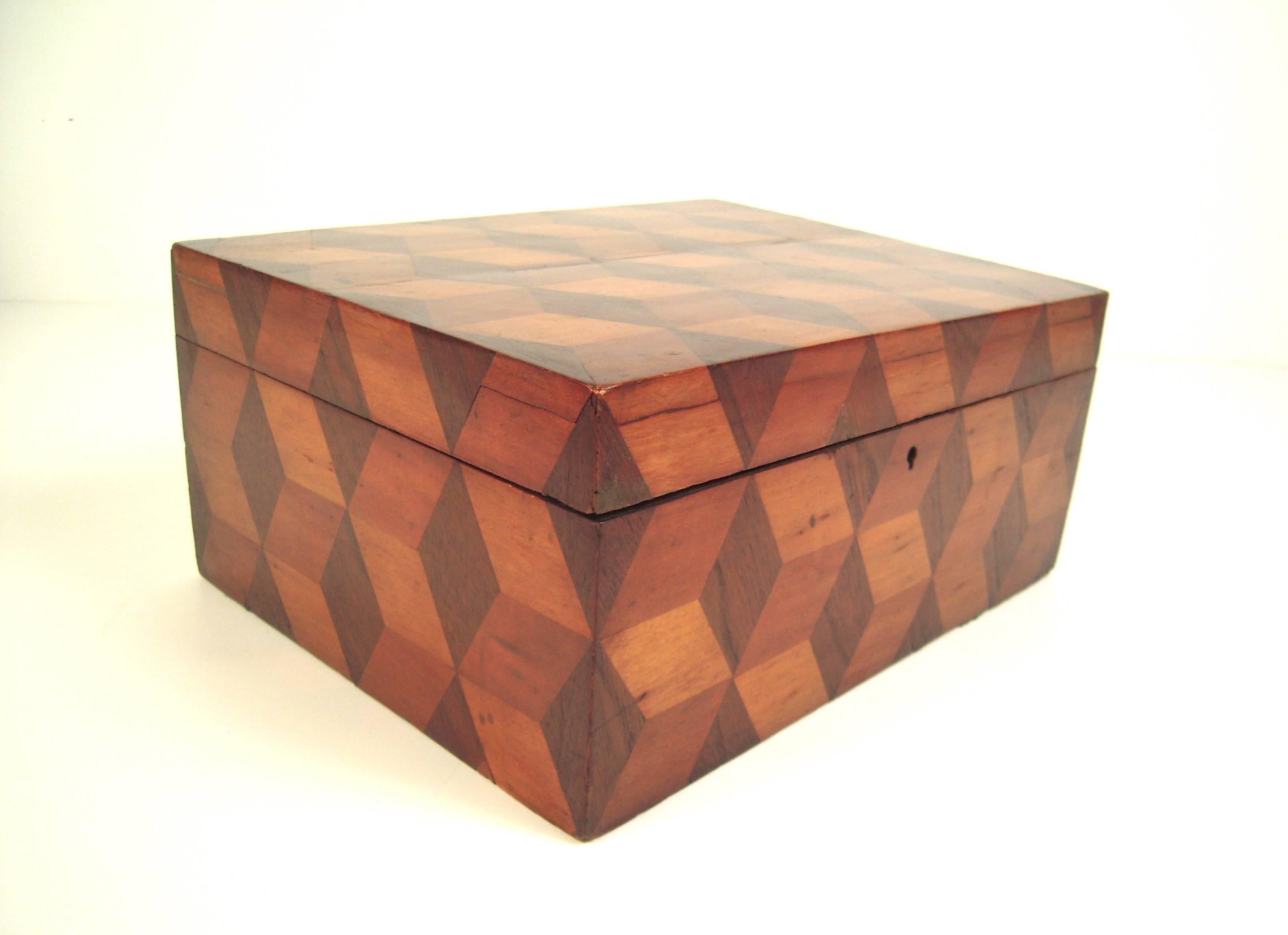 A graphic, 19th century American rectangular marquetry box, inlaid with contrasting light and dark woods, in the tumbling block pattern which is three dimensional and 