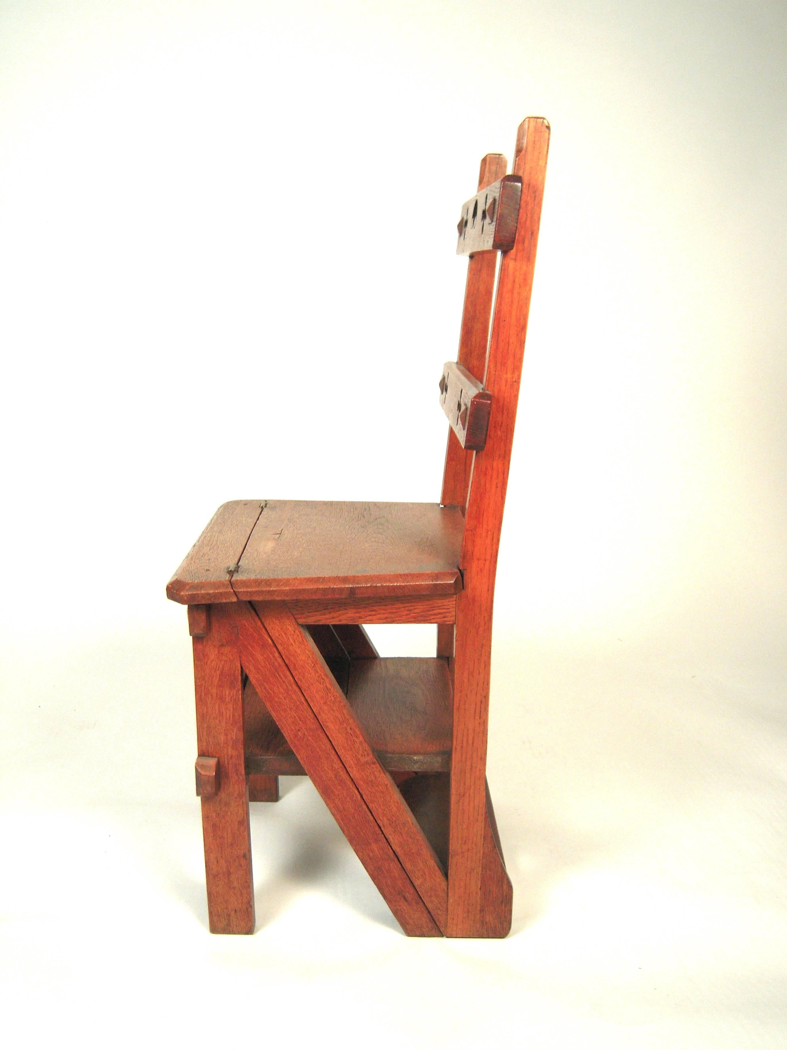 A well made and detailed Gothic Revival metamorphic combination chair and step ladder in carved oak, circa 1875, the rectangular back supports with cut out quatrefoil and crescent decoration over the hinged, square seat which flips over to form the