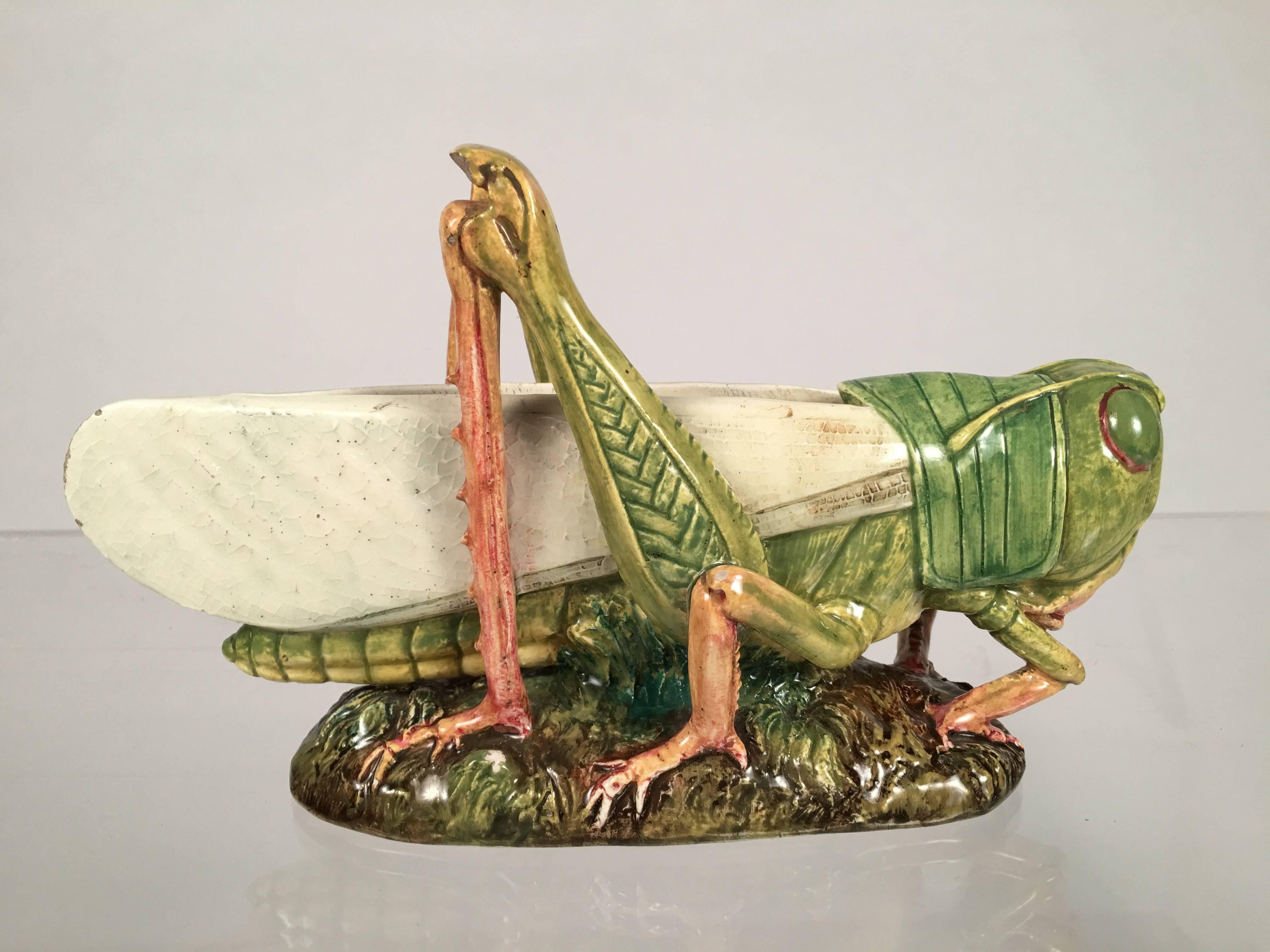 A naturalistically modeled and beautifully colored French majolica vase in the form of a grasshopper, by Delphin Massier, Vallauris (A.M.), France, circa 1880-1900. Signed in black on the underside of the oval base.
    