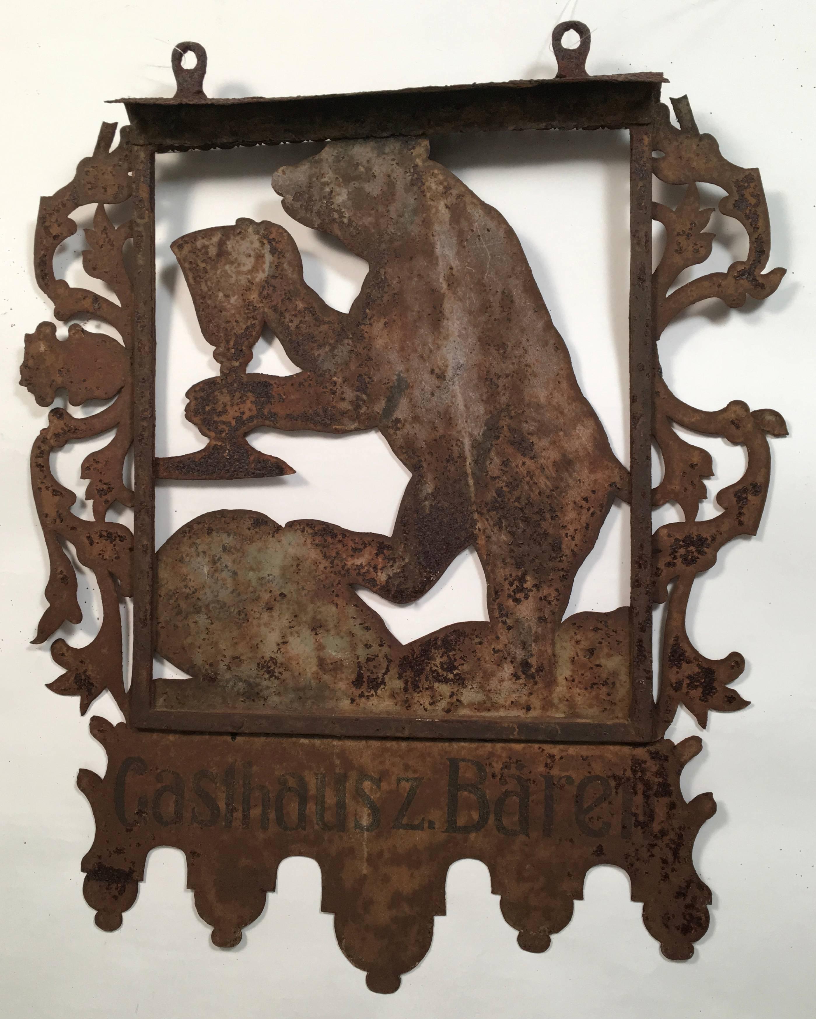 A charming and original antique sign from a Swiss Inn, the Gasthaus zum Bären, Inn of the Bears, showing a welcoming bear raising his (or her) glass, surrounded by a decorative scrolled foliate border, with geometric decoration along the bottom, on