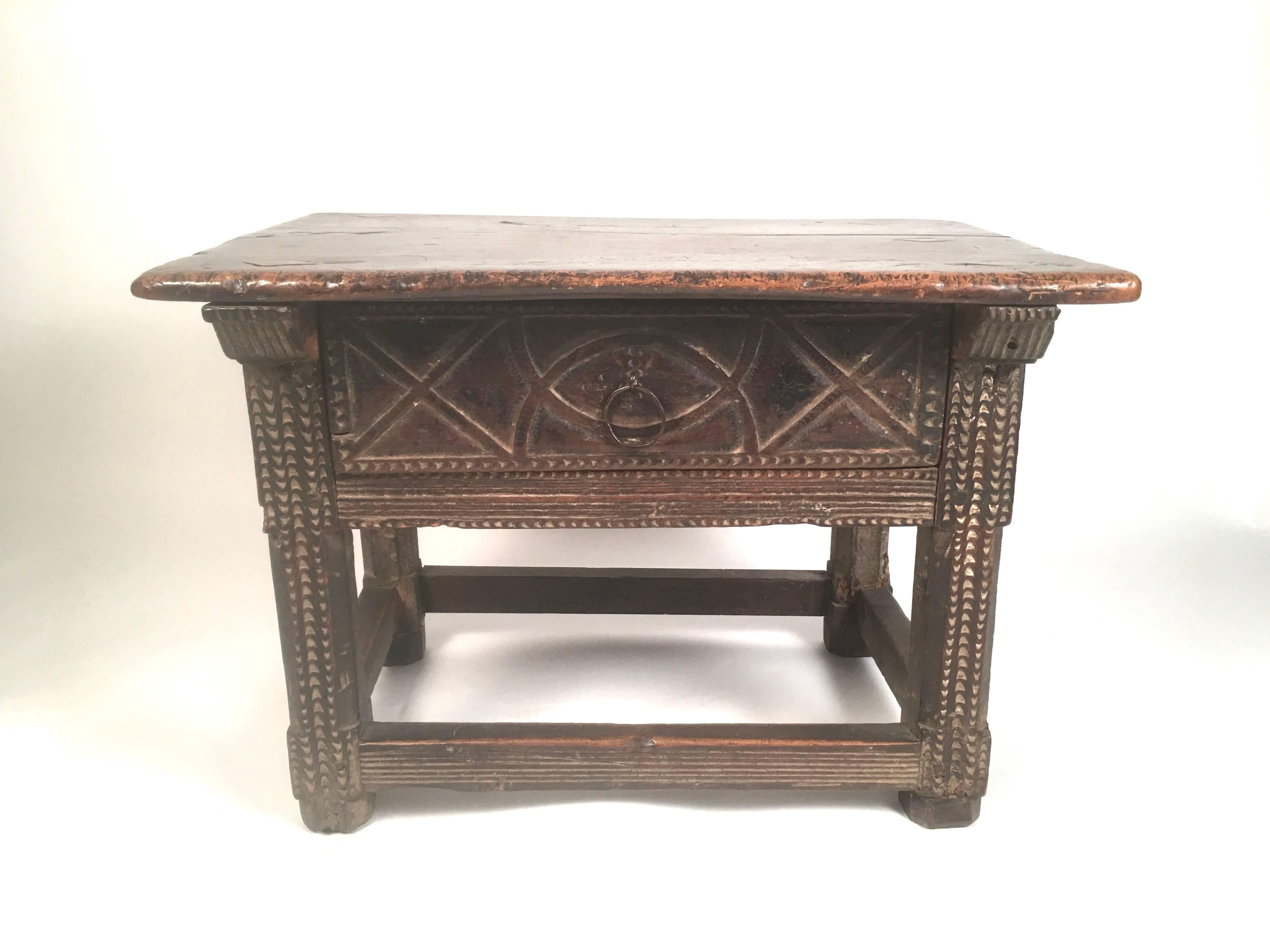 A Spanish Colonial carved oak and walnut occasional low table, perfect as a coffee table, too, with a beautifully patinated walnut rectangular top over a single deep drawer, intricately carved with geometric designs, with metal ring pull, supported