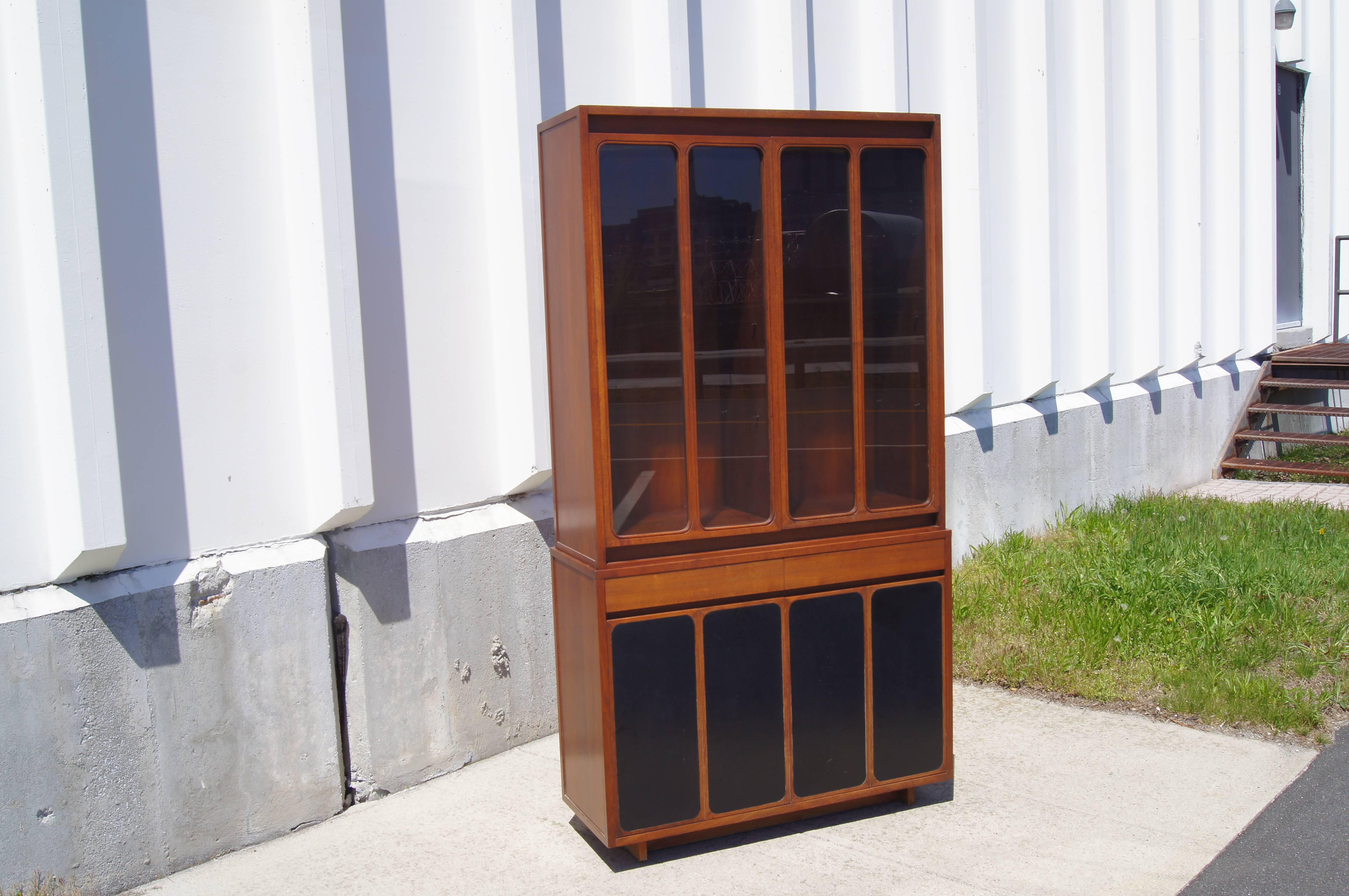 In this handsome Paul McCobb–designed cabinet, oiled walnut frames glass and leather-fronted cases. The upper display case has six adjustable glass shelves; the lower case features two wide drawers above generous storage, with two adjustable shelves