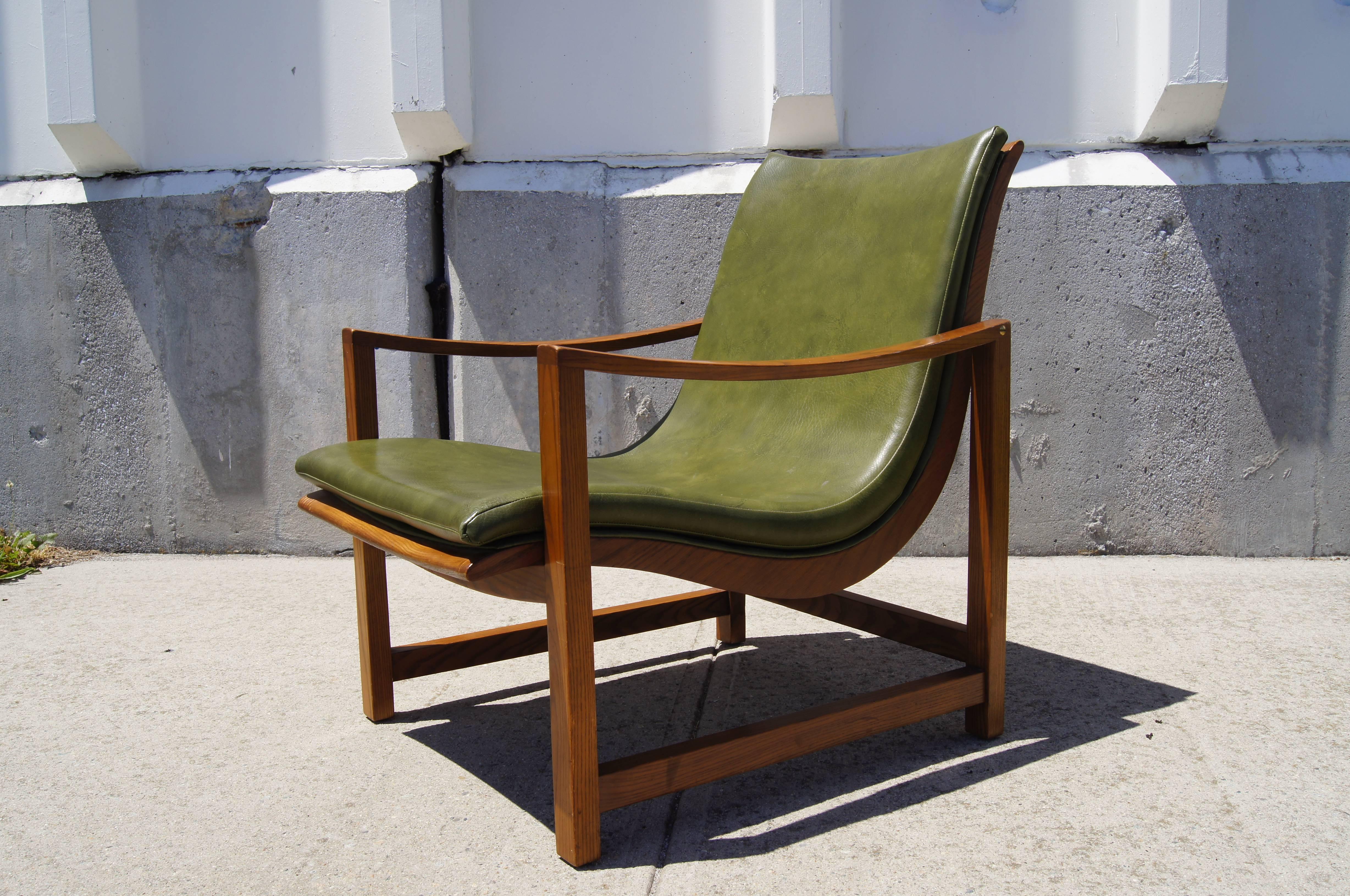 This rarely seen lounge chair, designed by Edward Wormley for Dunbar, sets a green leather-embossed vinyl sling seat into an elegant frame of ash that opposes a rectilinear base with curved arms.