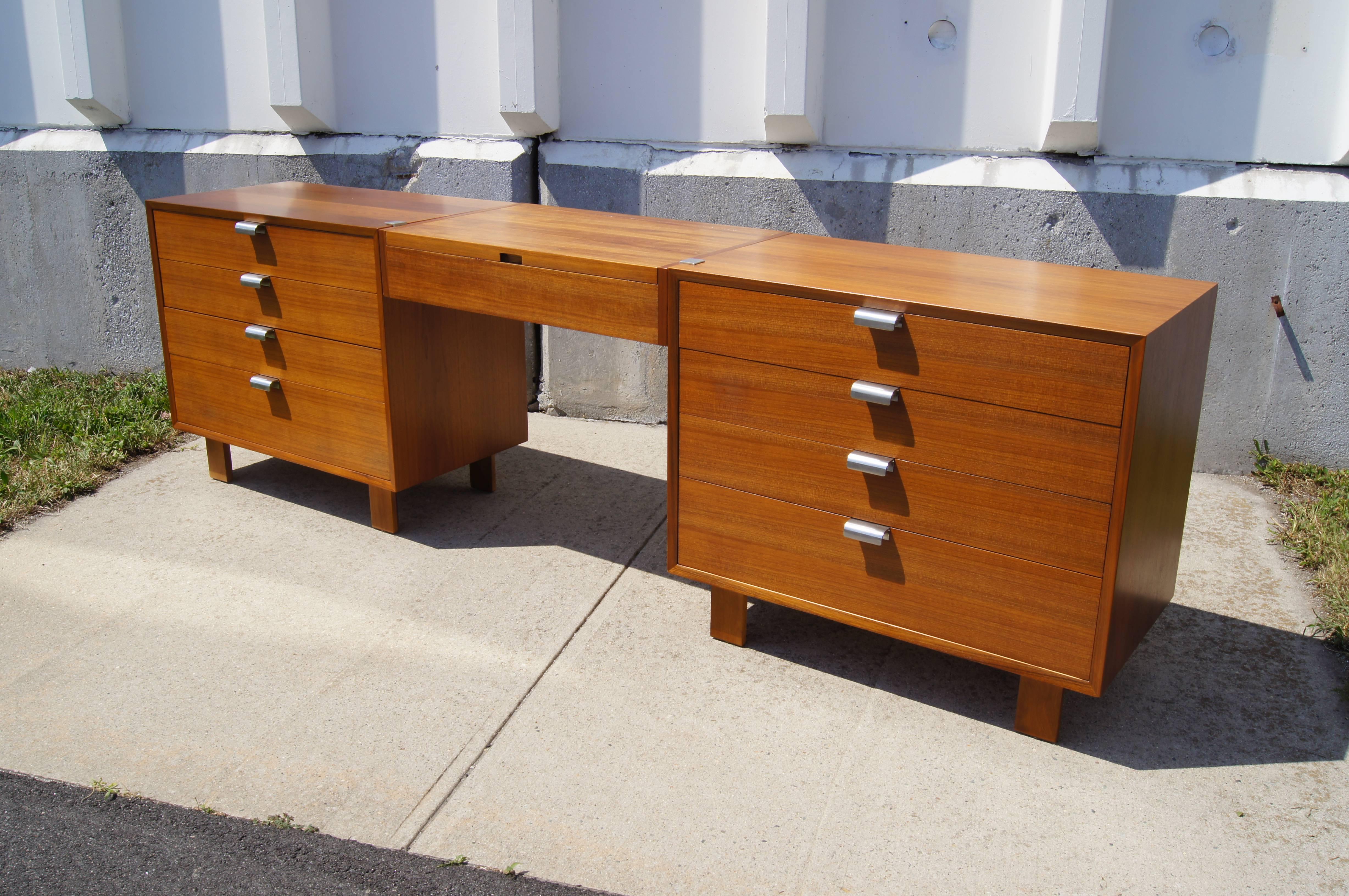 Part of the basic storage components that George Nelson designed for Herman Miller in 1952, this extraordinary set comprises two dressers in a warm walnut on either side of a suspended vanity.

Each 34-inch-wide dresser contains four drawers with