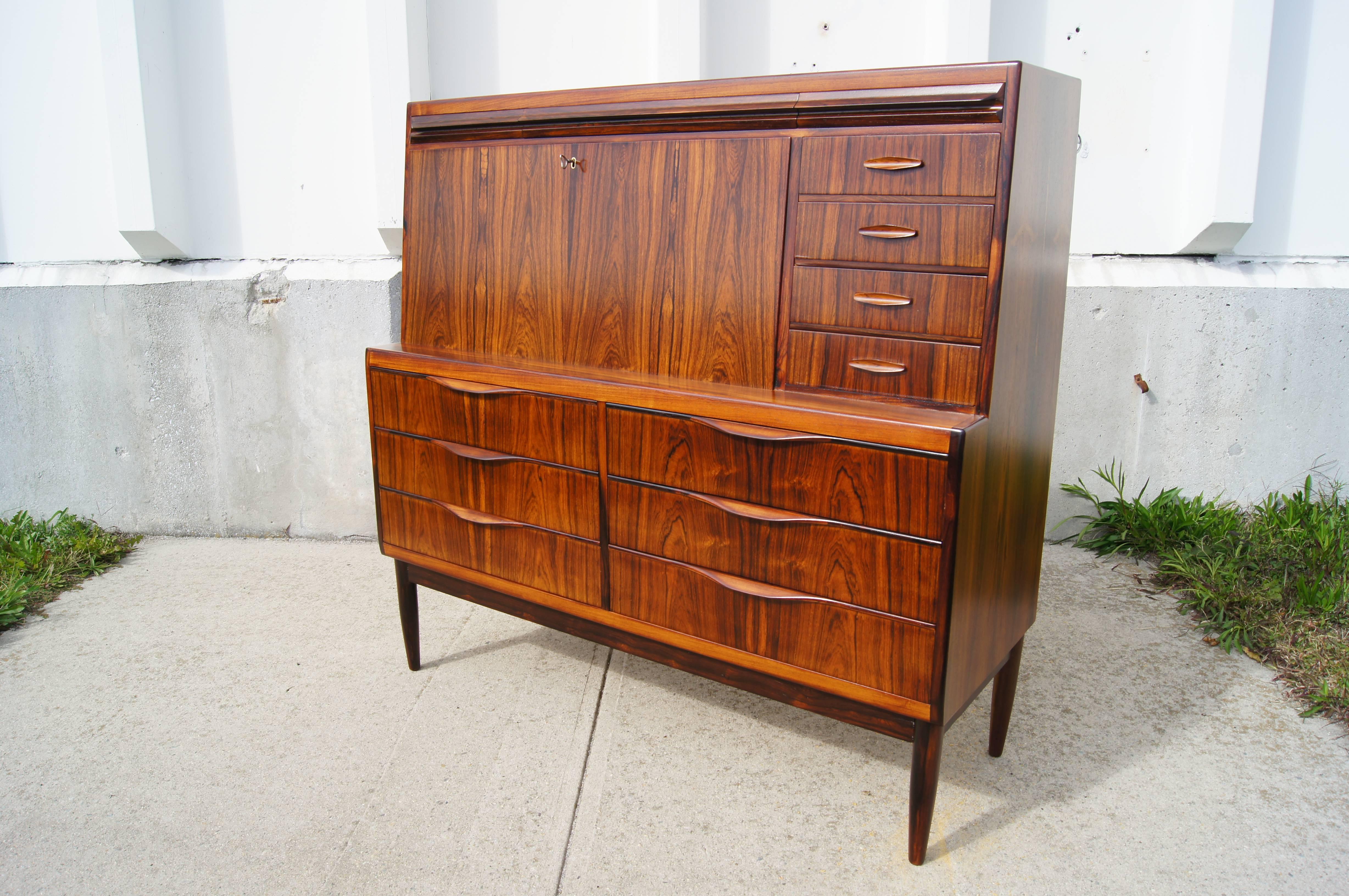 Designed by Erling Torvits for Klim Møbelfabrik, this exquisite secretaire takes full advantage of its richly grained Brazilian rosewood. The case sits on slender tapered feet, with six large drawers at the bottom. A locking desktop folds down to