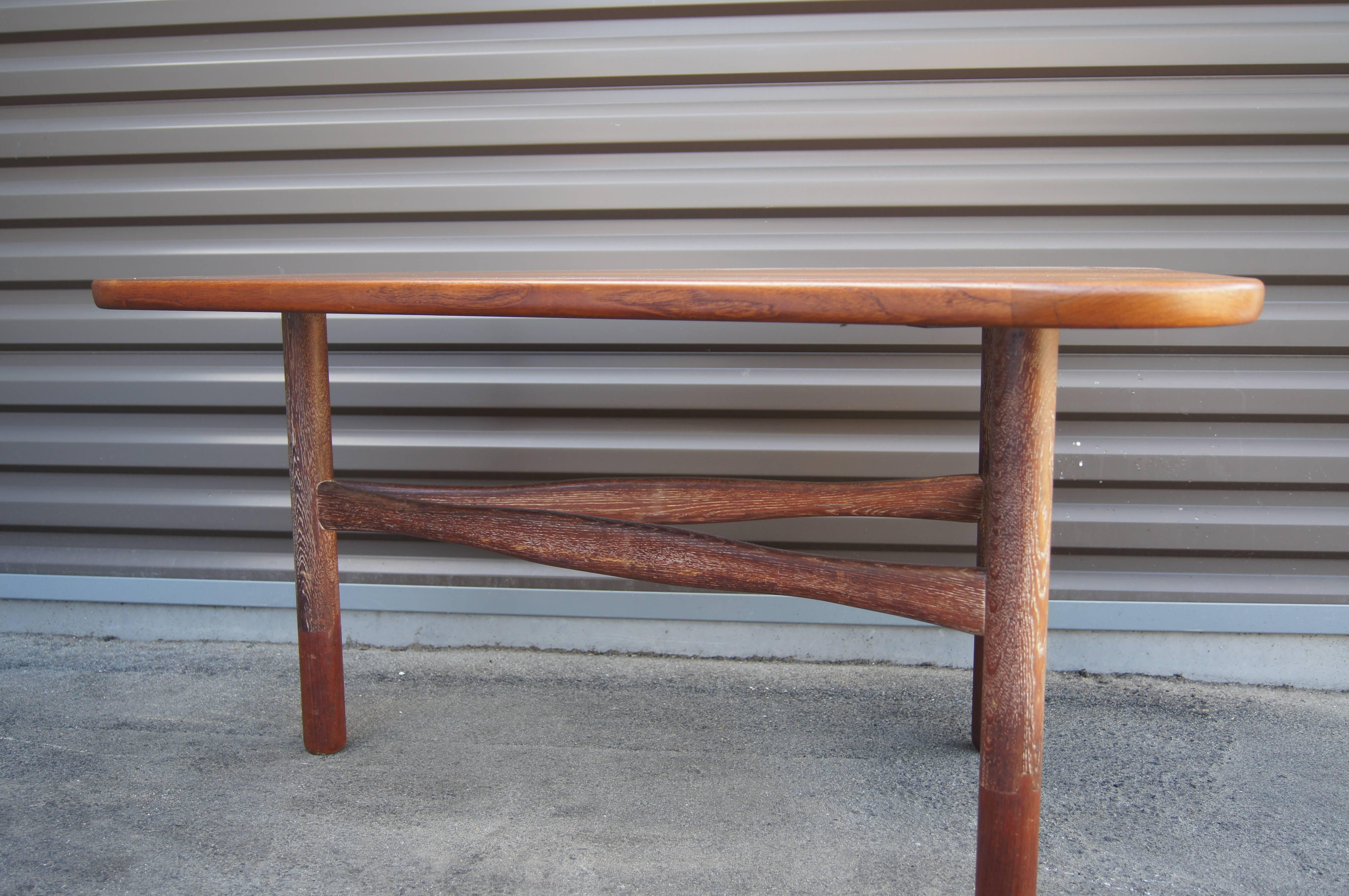 This unusual Swedish modern table, designed by Yngve Ekström for Westbergs Möbler, places an irregularly shaped teak top (narrowing from 36 inches to 15 inches) on a three-legged base of carved and cerused oak. It would work equally well behind a