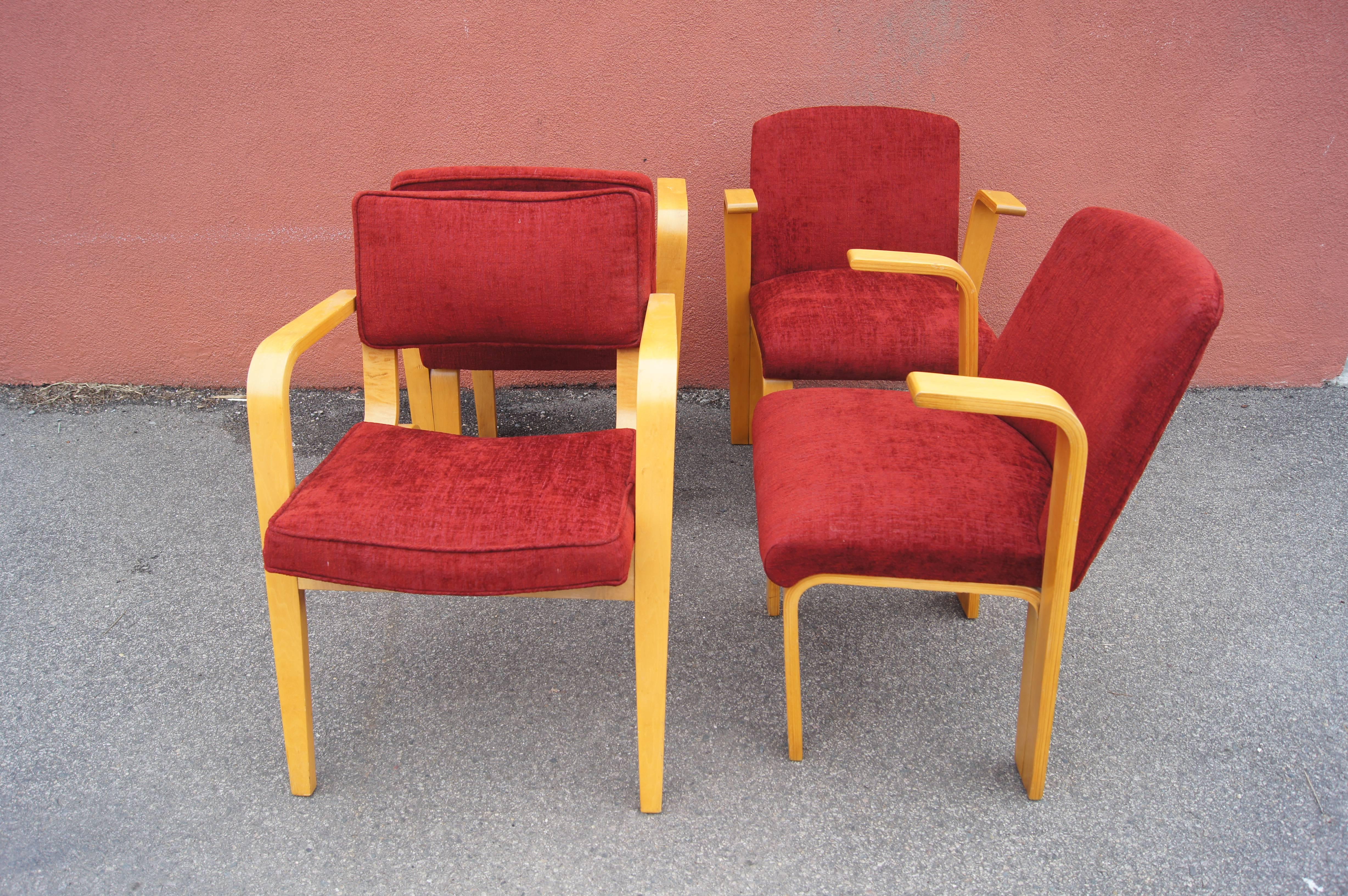 Upholstered in a soft textile in vibrant red, these four birch armchairs are classic modernist bentwood by Thonet. Three chairs, attributed to Joe Atkinson, sport solid seat backs and abbreviated armrests that emerge from the hairpin back legs. The