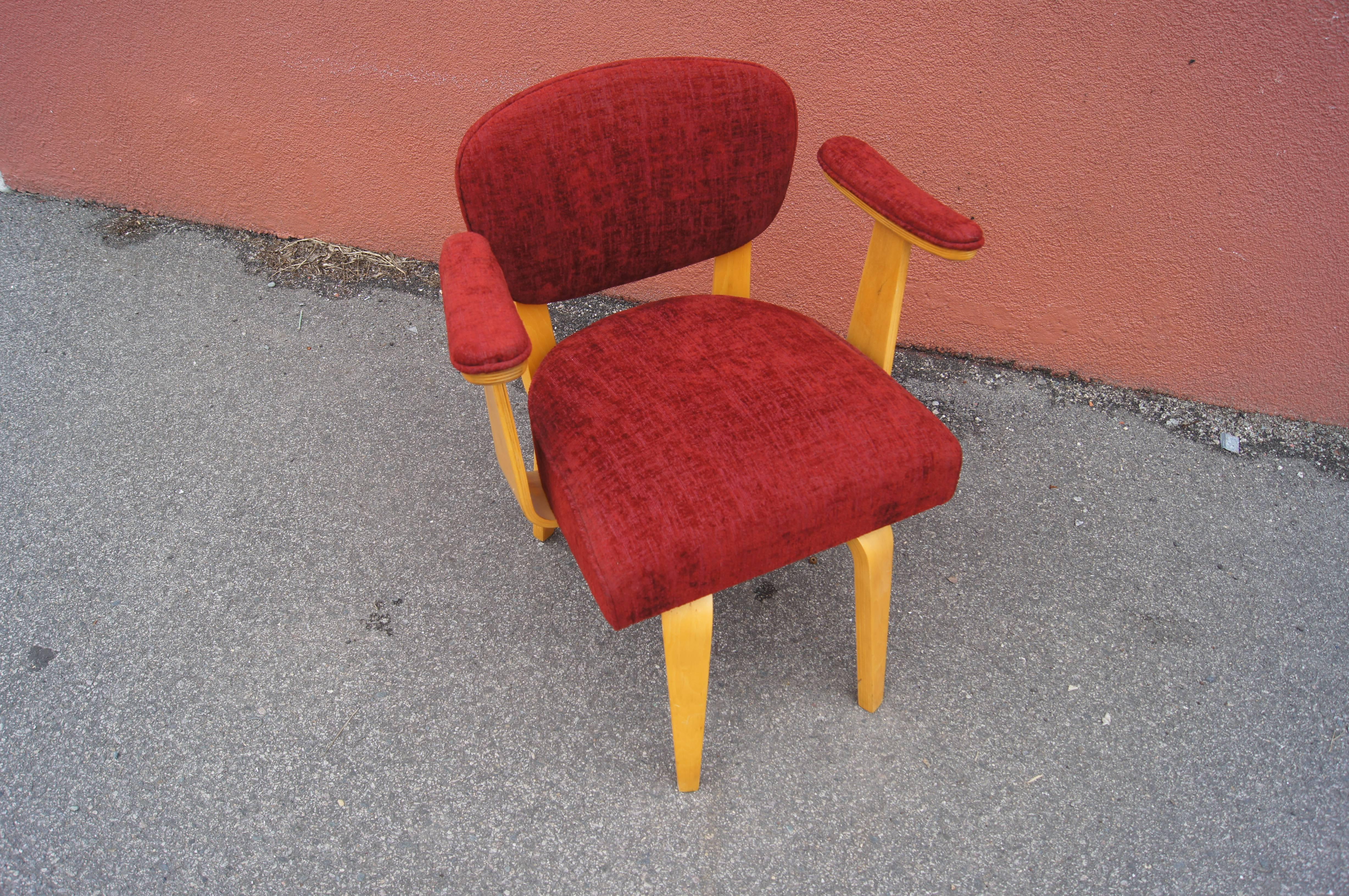 Upholstered in a soft textile in vibrant red, this Thonet armchair is classic modernist birch  bentwood with a punch. The rounded seat and seat back rise above tapered legs. The perky armrests are padded.

A set of four corresponding armchairs is