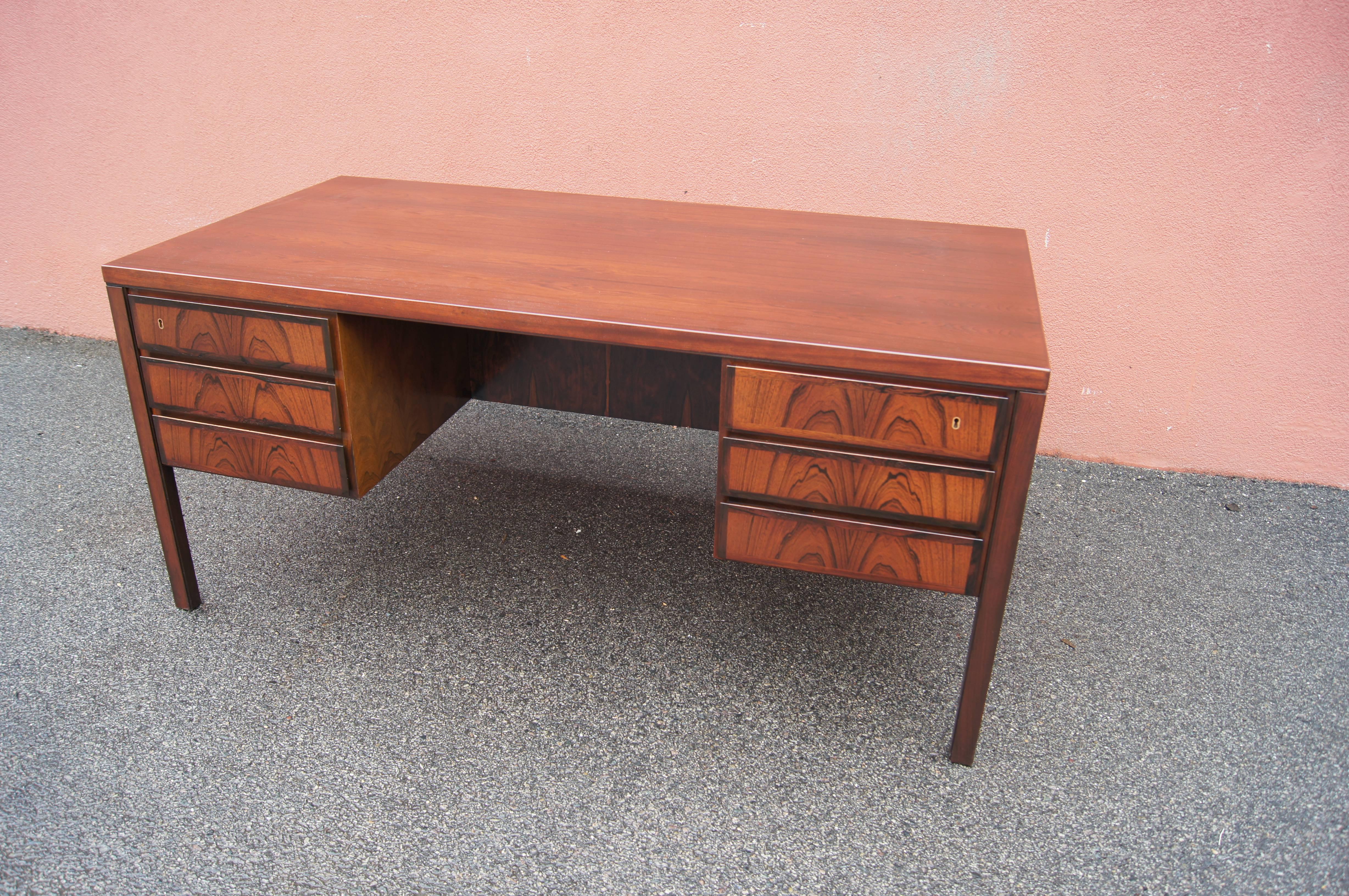 Gunni Omann designed this handsome, clean-lined rosewood desk, model 77, for Omann Jun Møbelfabrik in the 1960s. Three drawers sit either side of the chair-well, one of which has a built-in pen tray. The front of the desk features more storage