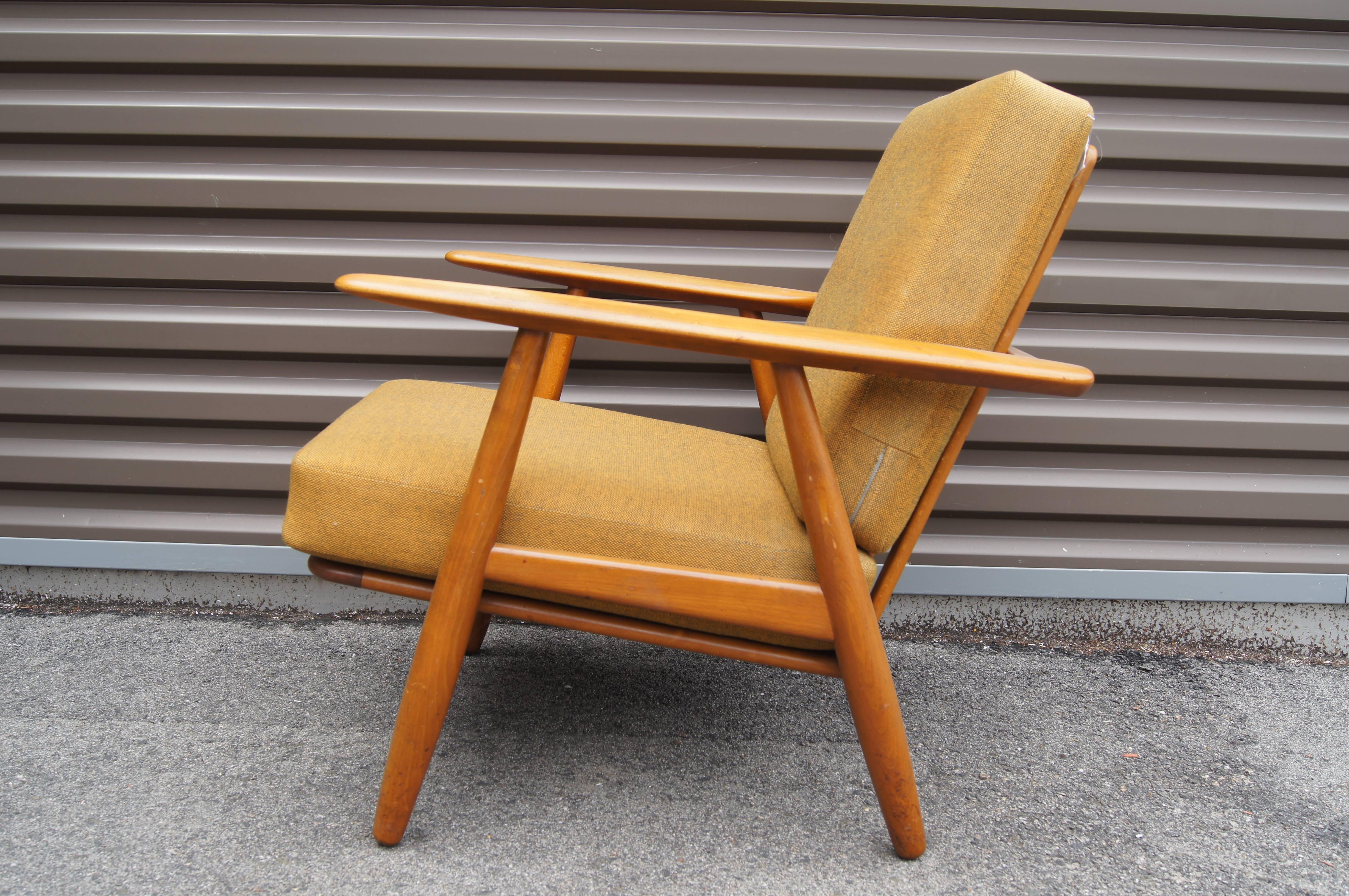 Hans Wegner designed the GE-240 in 1955 for GETAMA. The gently curved lines of the armrests inspired the name Cigar chair. This comfortable lounge chair has a lovely oak frame and its original sprung cushion upholstered in a subtle mustard-colored