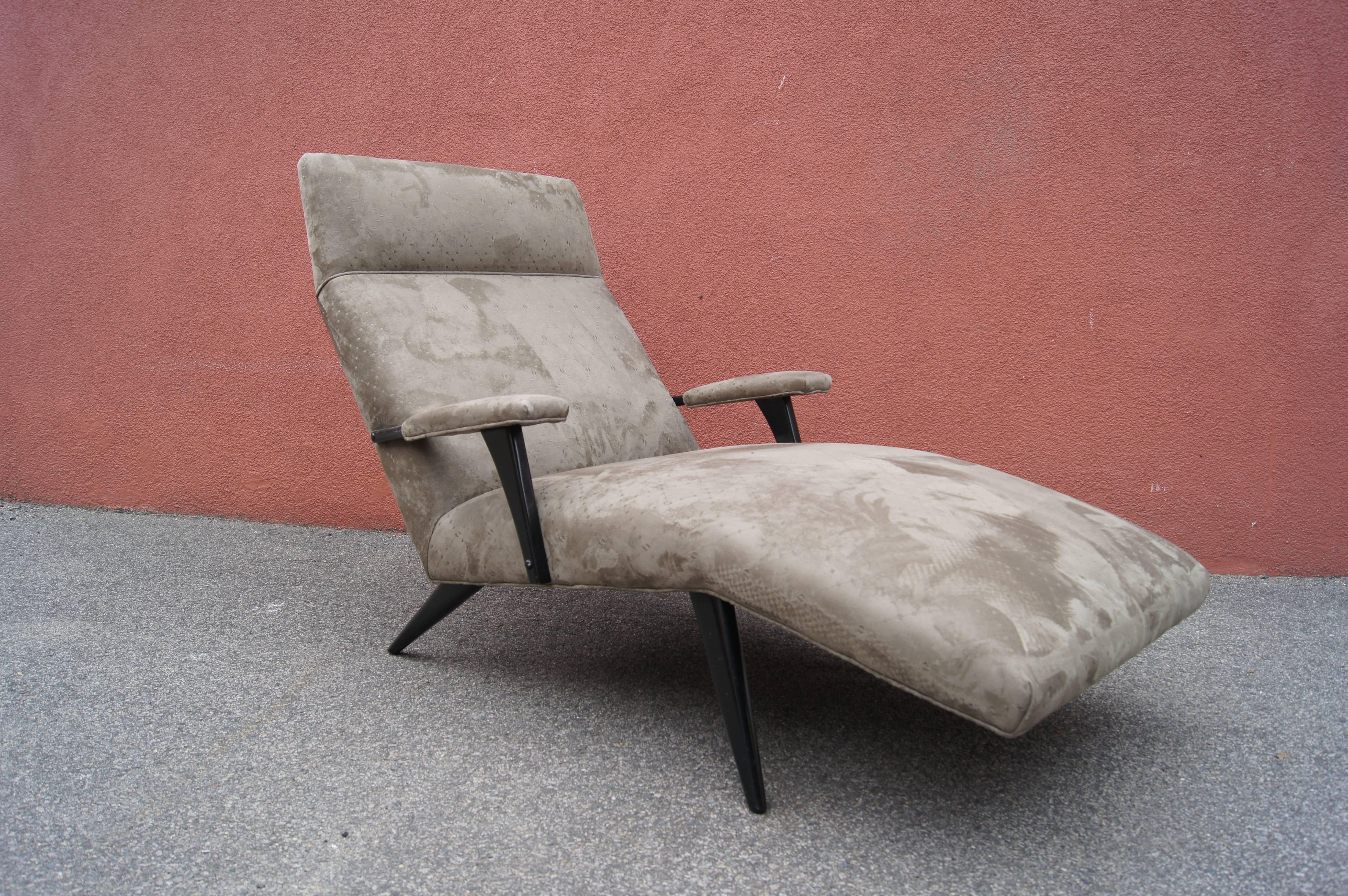 This 1950s chaise longue features a sweeping frame upholstered in a soft and restful moss-green microsuede with black-lacquered legs and arms.