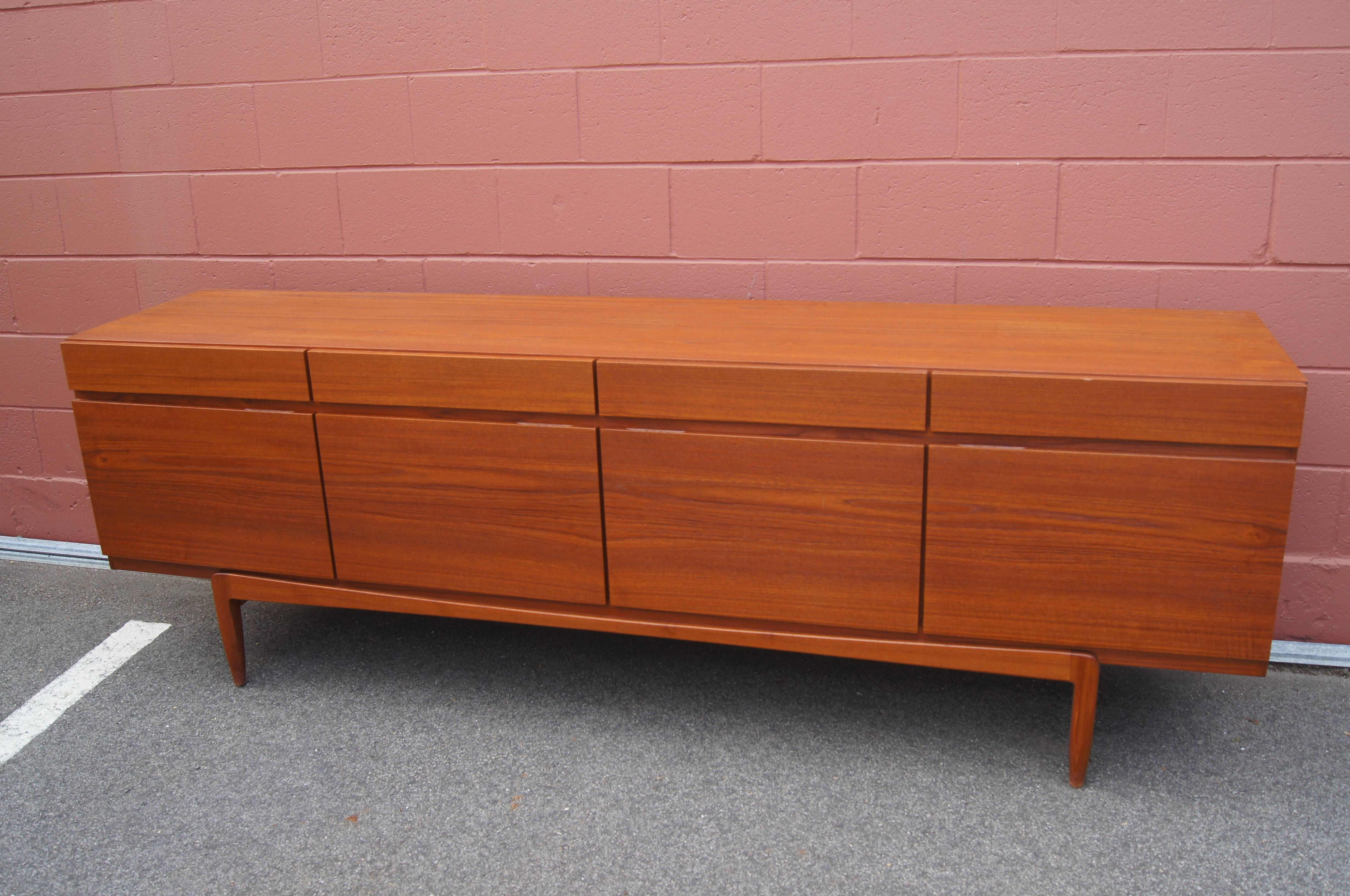 This handsome mid-century sideboard, model 66 by Ib Kofod-Larsen for Faarup, is solidly constructed, with minimal, clean lines. Set on a raised base, the teak case provides ample storage. Four roomy drawers are aligned above four doors; five