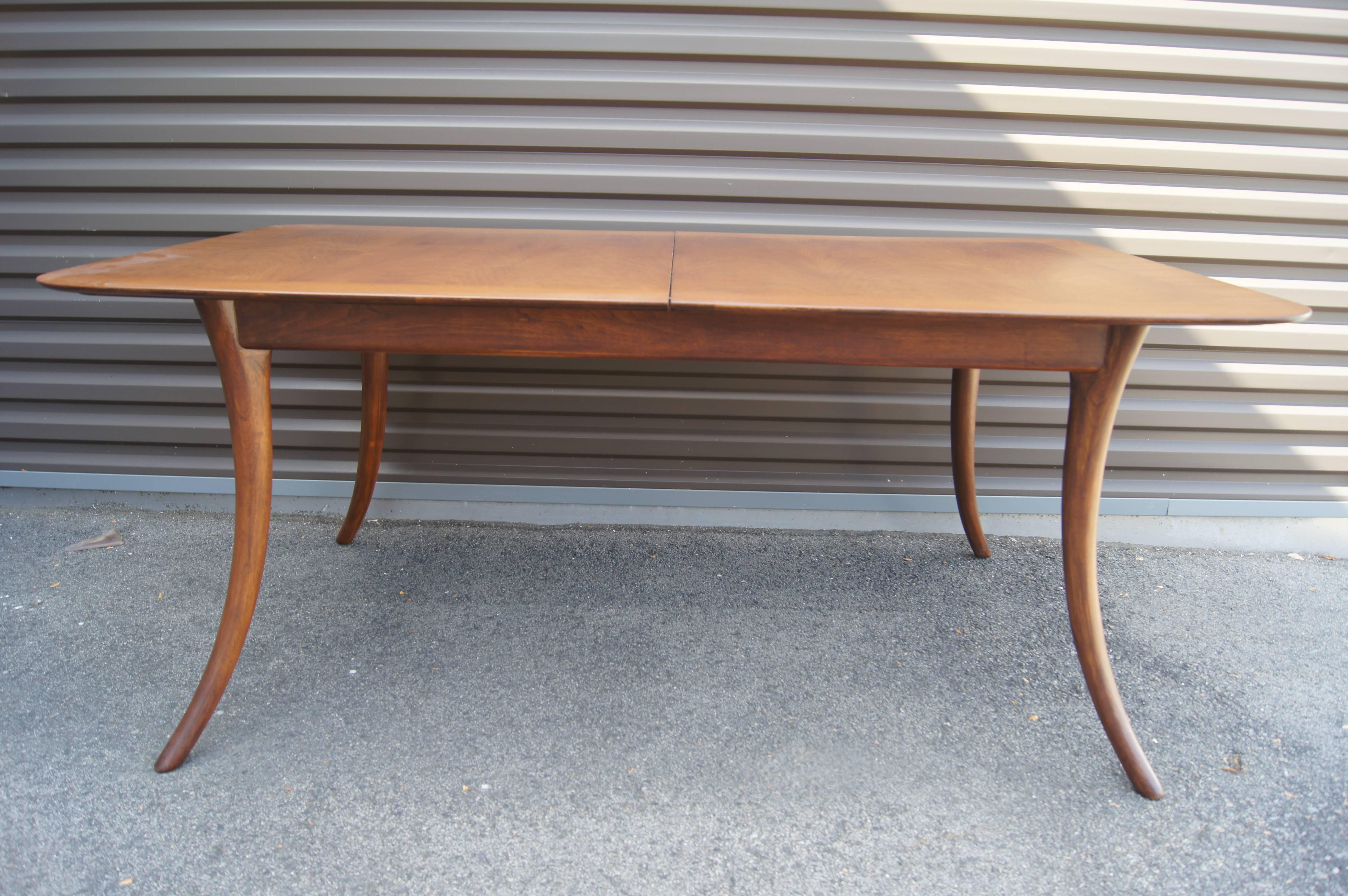 Designed by T.H. Robsjohn-Gibbings for Widdicomb, this large mahogany dining table features elegant saber legs. The table has two leaves, each measuring 18