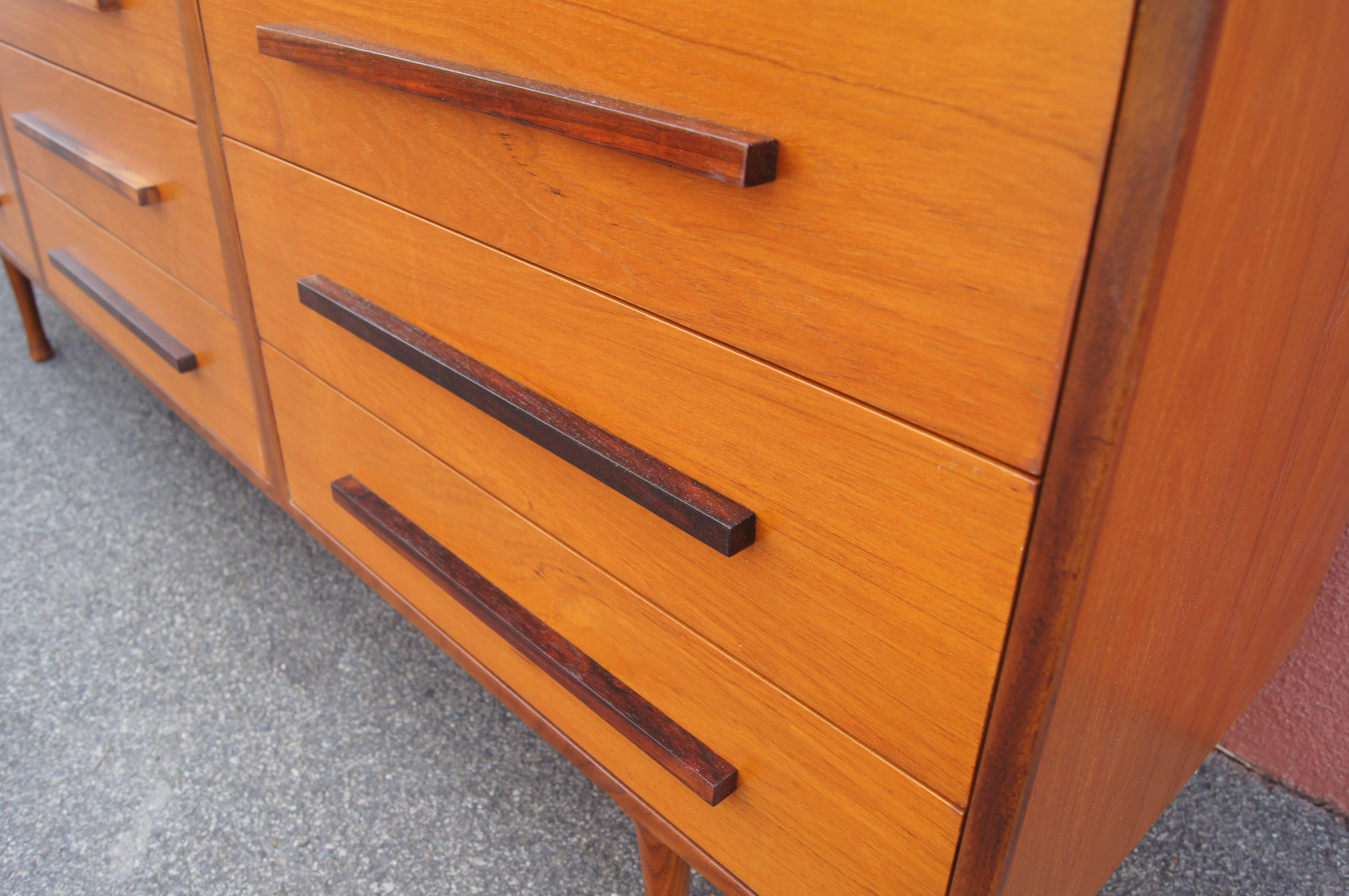 This fabulous Danish modern dresser surrounds a teak case on a plinth base with a rosewood frame. Contrasting rosewood pulls on the nine drawers emphasize its regularity and linearity.

 