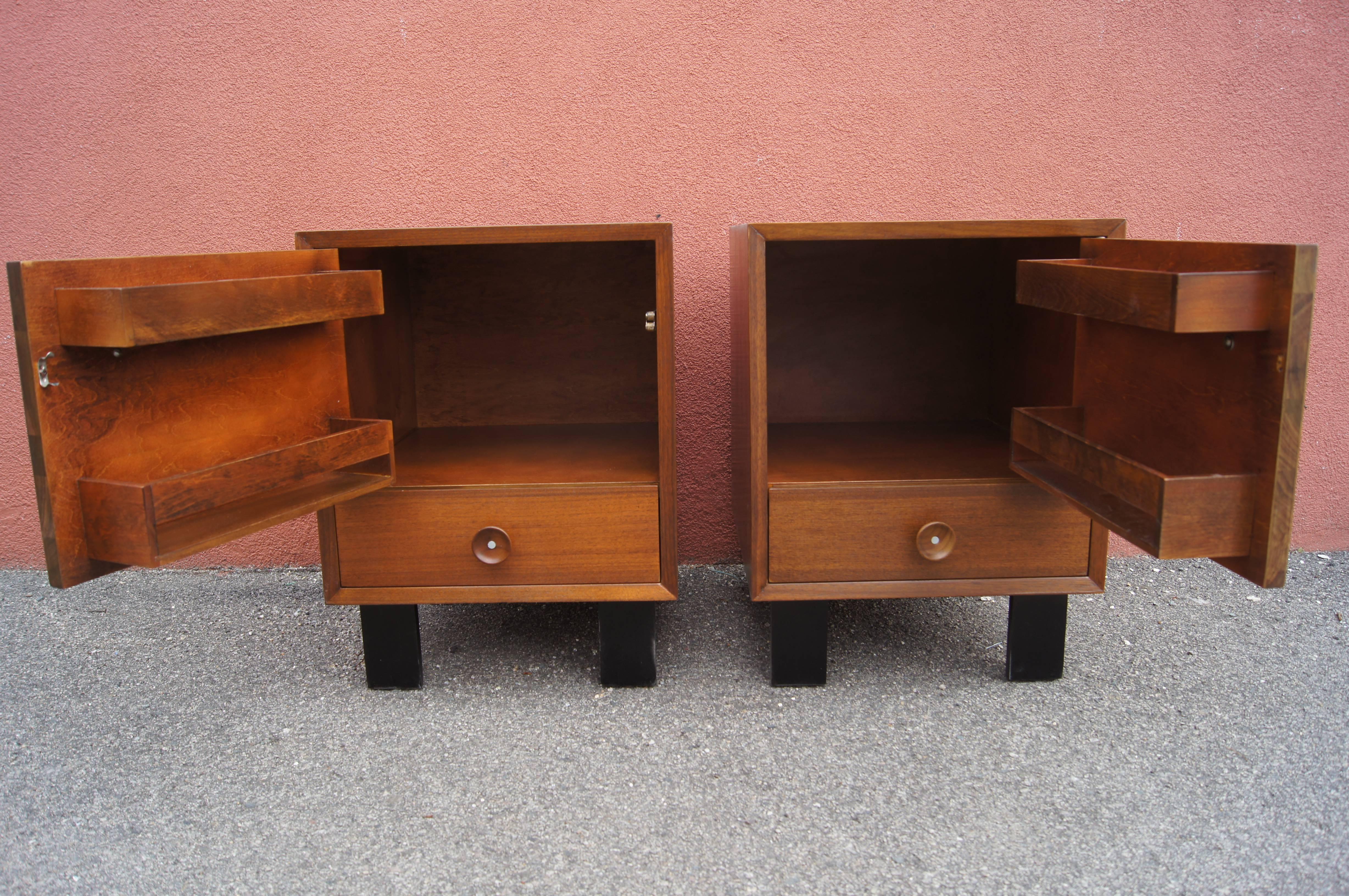 George Nelson designed this handsome pair of nightstands, model 4617, for Herman Miller's basic Cabinet Series. The tawny walnut cases have a right- and a left-facing hinged door fitted with two shallow shelves. Below the storage cabinet is a single