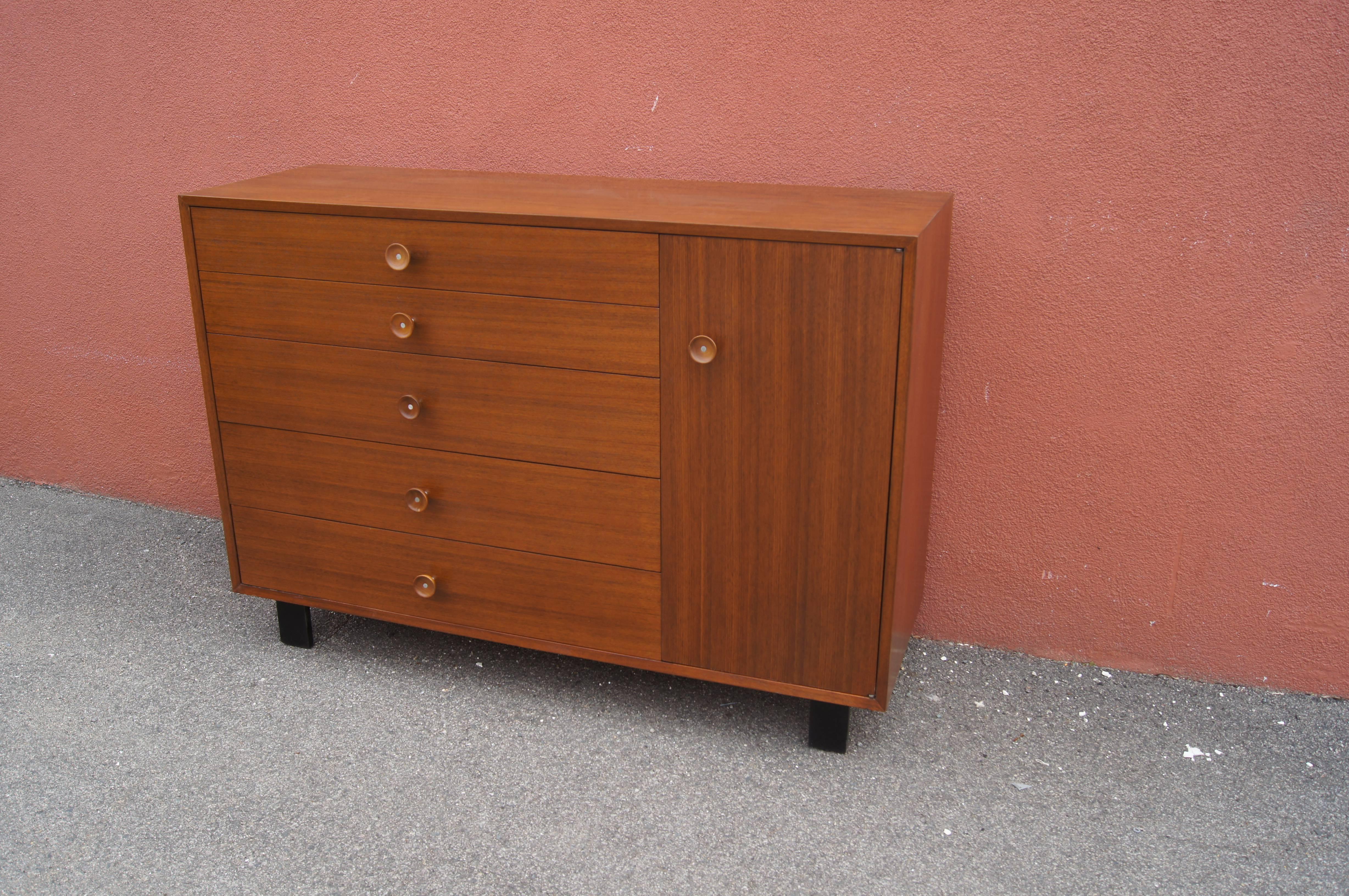 George Nelson designed this handsome dresser or cabinet, model 4935, for Herman Miller's Basic cabinet series. The tawny walnut case comprises five drawers on the left with dividers in the first and third drawers and a cabinet on the right with two
