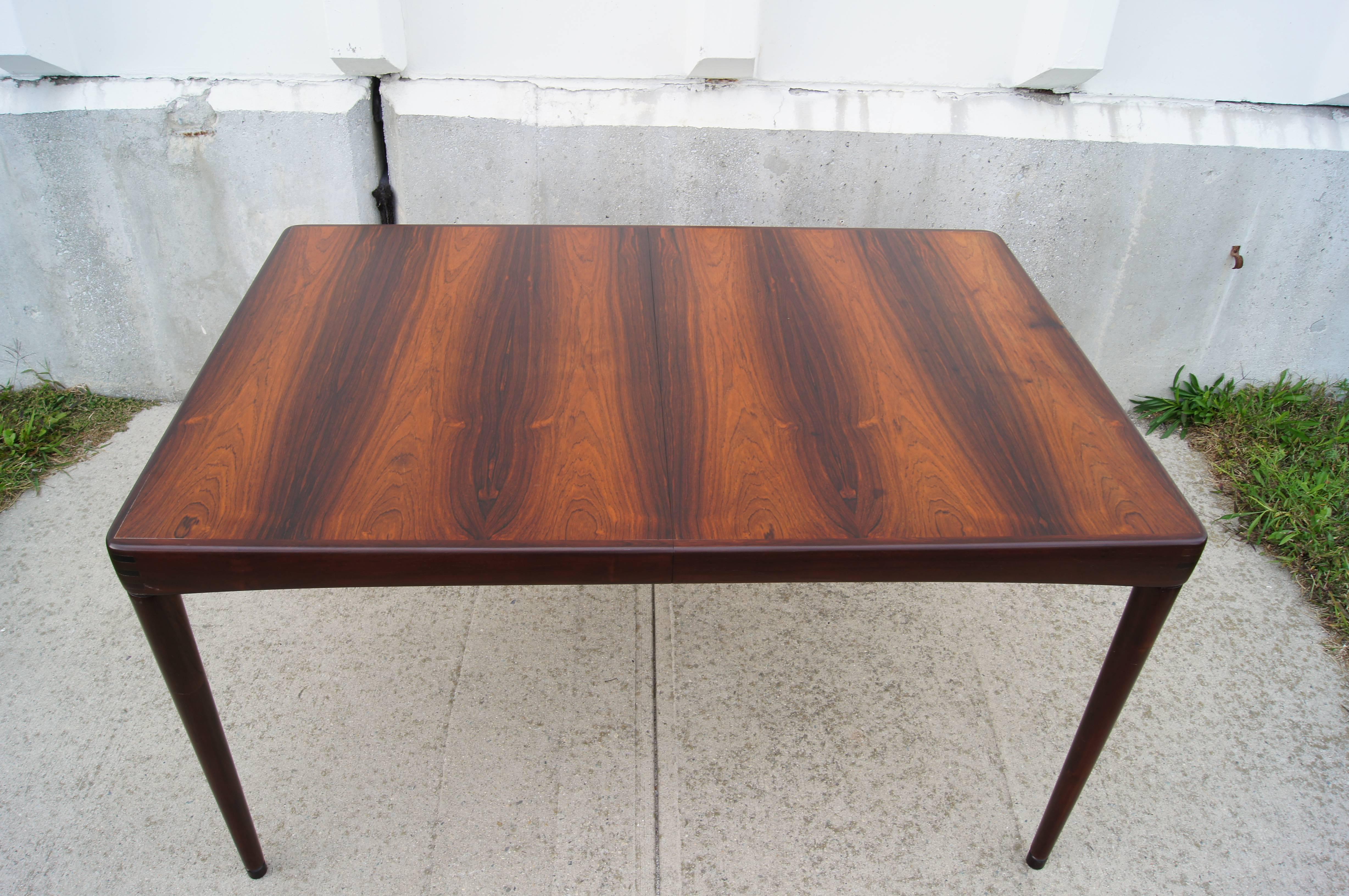 This dining table was designed by H.W. Klein and manufactured by Bramin Mobler. It is features a beautiful rosewood top with round, tapered legs and unique joinery at the corners. The table includes one 23.75″ leaf that allows it to extend up to