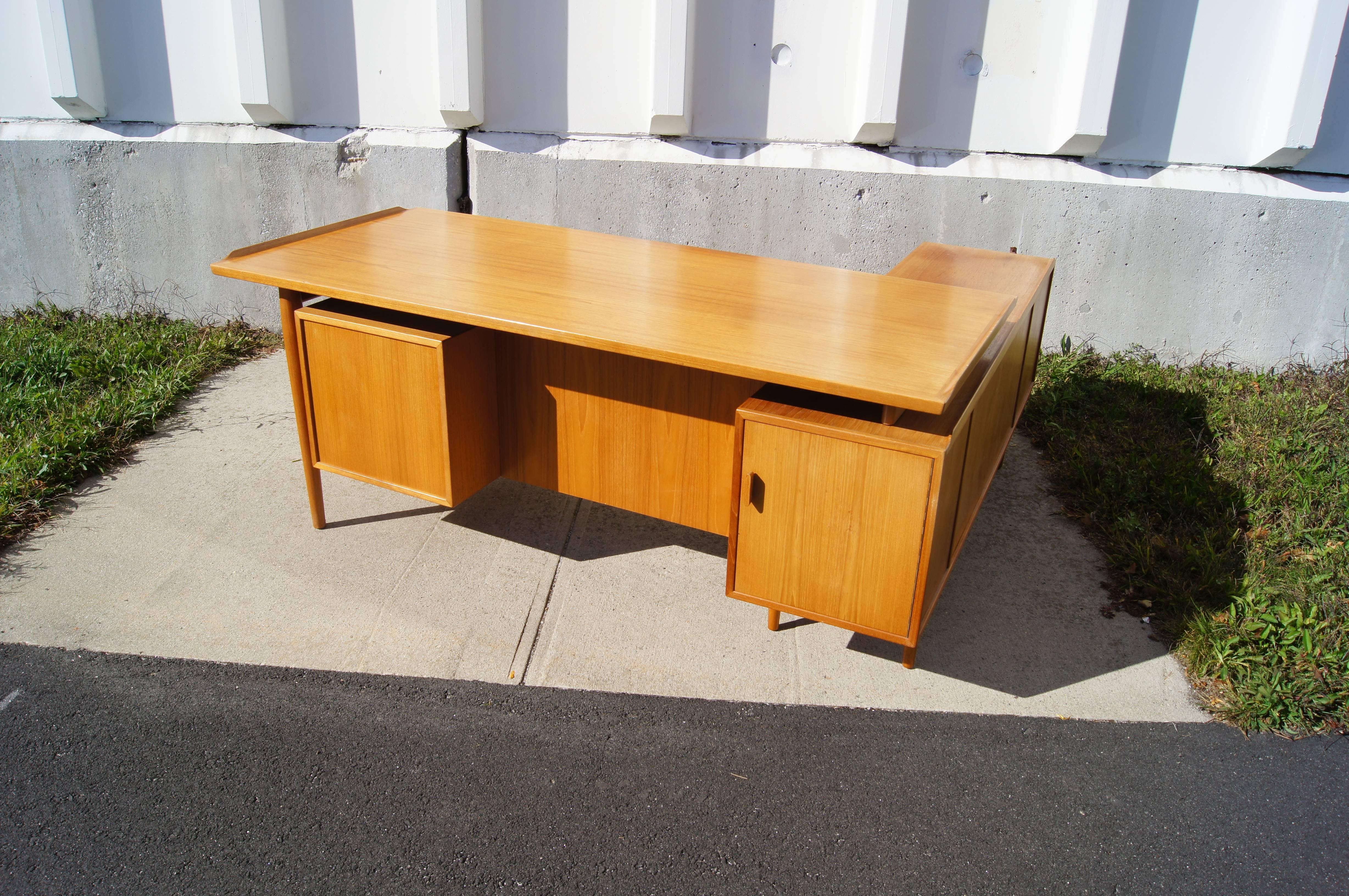 This desk was designed by Arne Vodder and manufactured in Denmark by Sibast. It is composed of two components, a large desk that rests on a lower credenza, that together form an L-shape. The desk has ample storage, including multiple drawers, a file