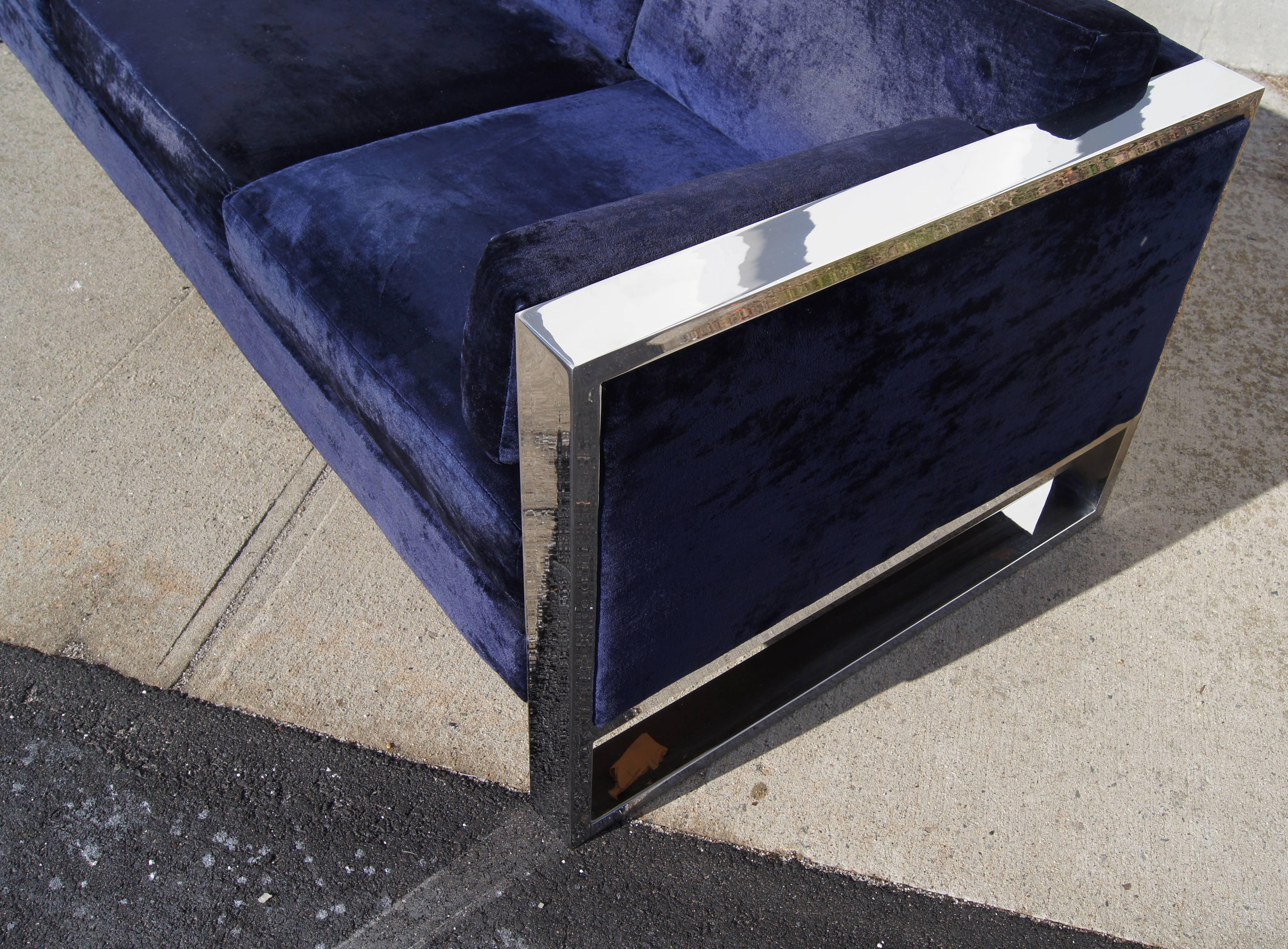 This sofa by Milo Baughman features blue velvet upholstery and a wide polished chrome frame.