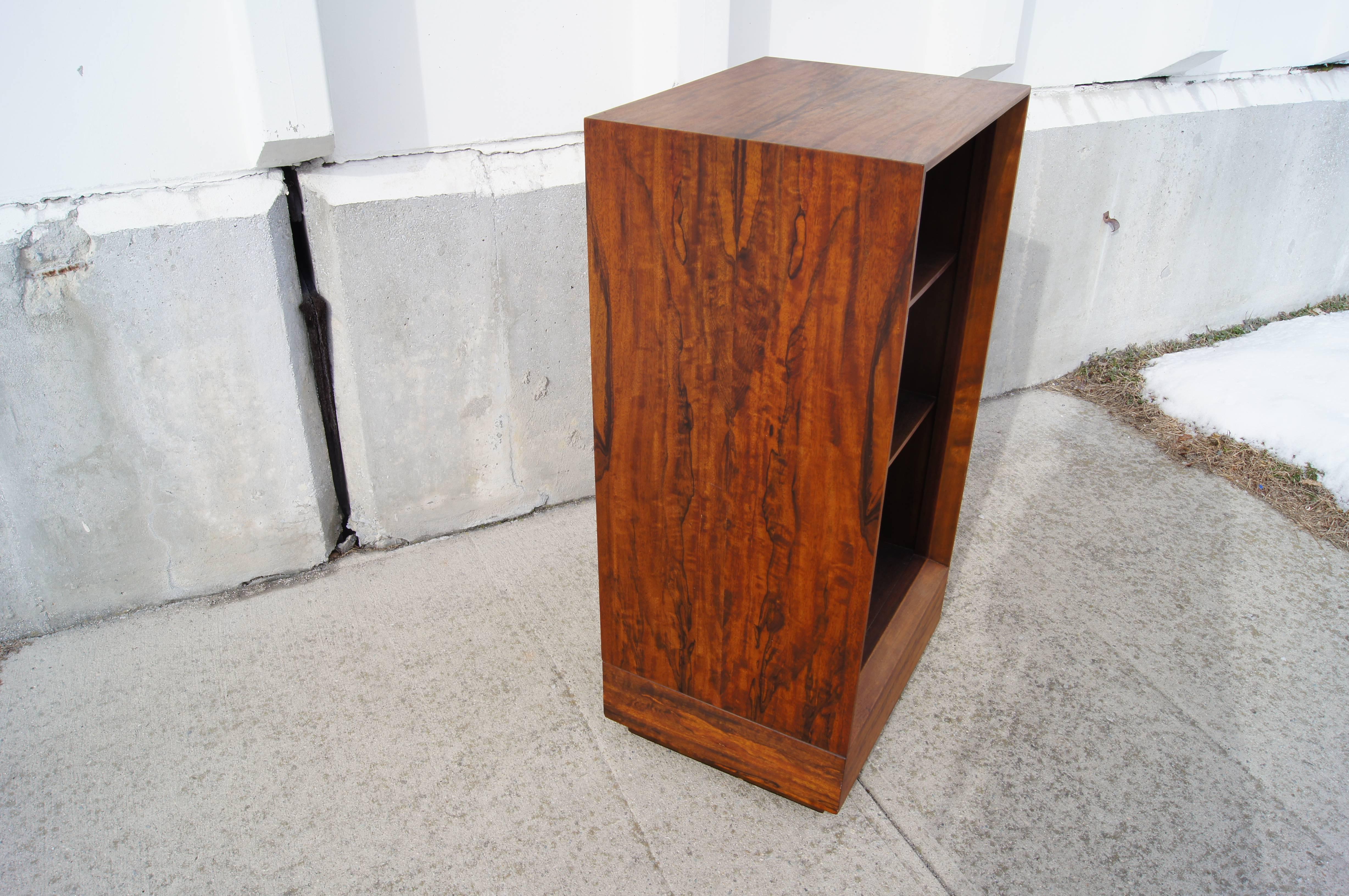 Gilbert Rohde created this handsome bookcase, number 4113, for Herman Miller in the 1940s. Made of paldao wood, it has two fixed shelves set into a bevel-edged case that rests on an inset plinth. Original finish.