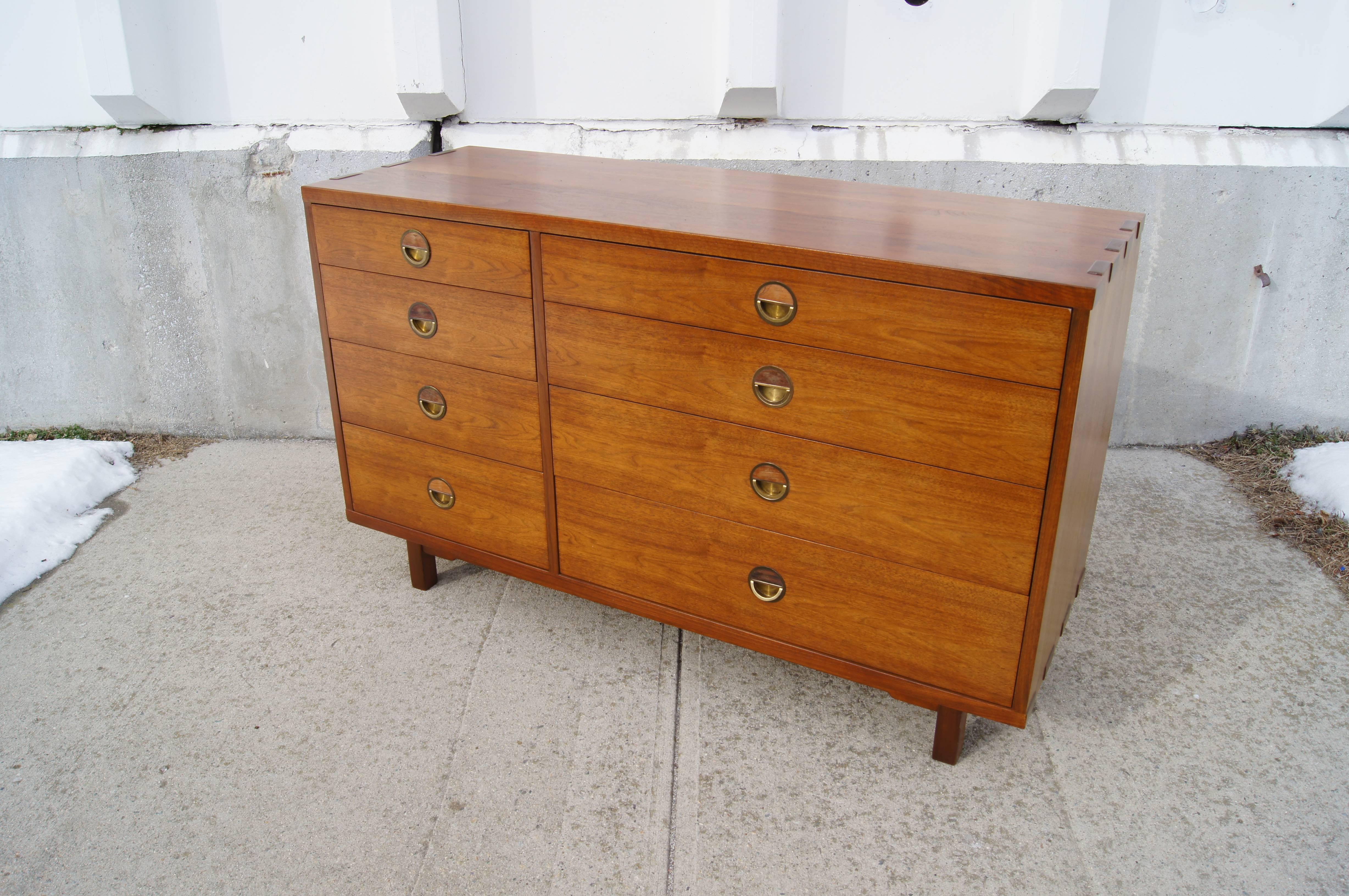 The eight drawers of this solid walnut dresser by Edward Wormley form an elegant asymmetry that is emphasized by the inset brass ring pulls. The sides feature bold overlapping finger joints. 