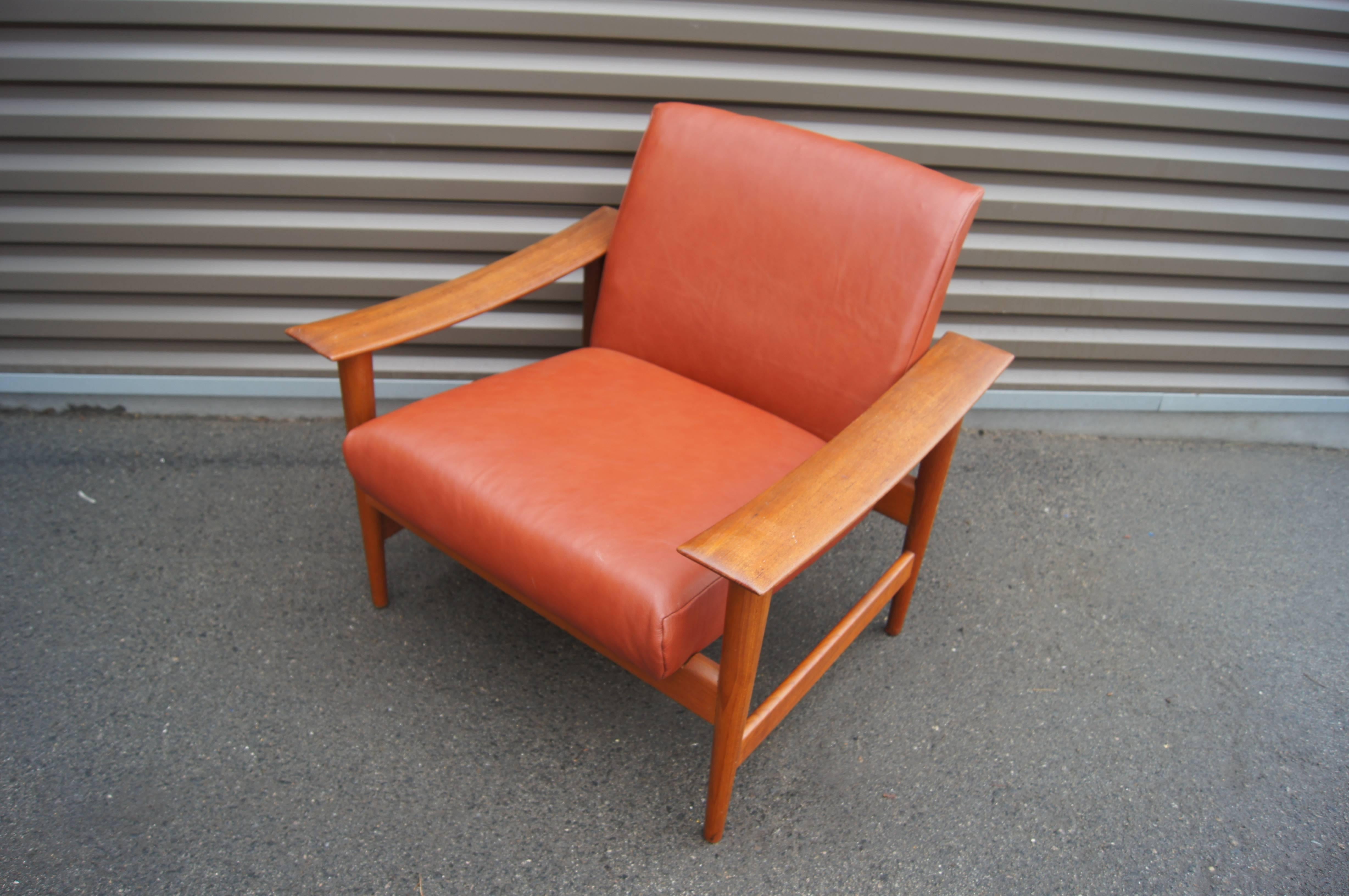 Its broad carved arms give this Danish modern lounge chair its distinctive character. The solid teak frame cradles a comfortable seat upholstered in a warm brick leather.
 
