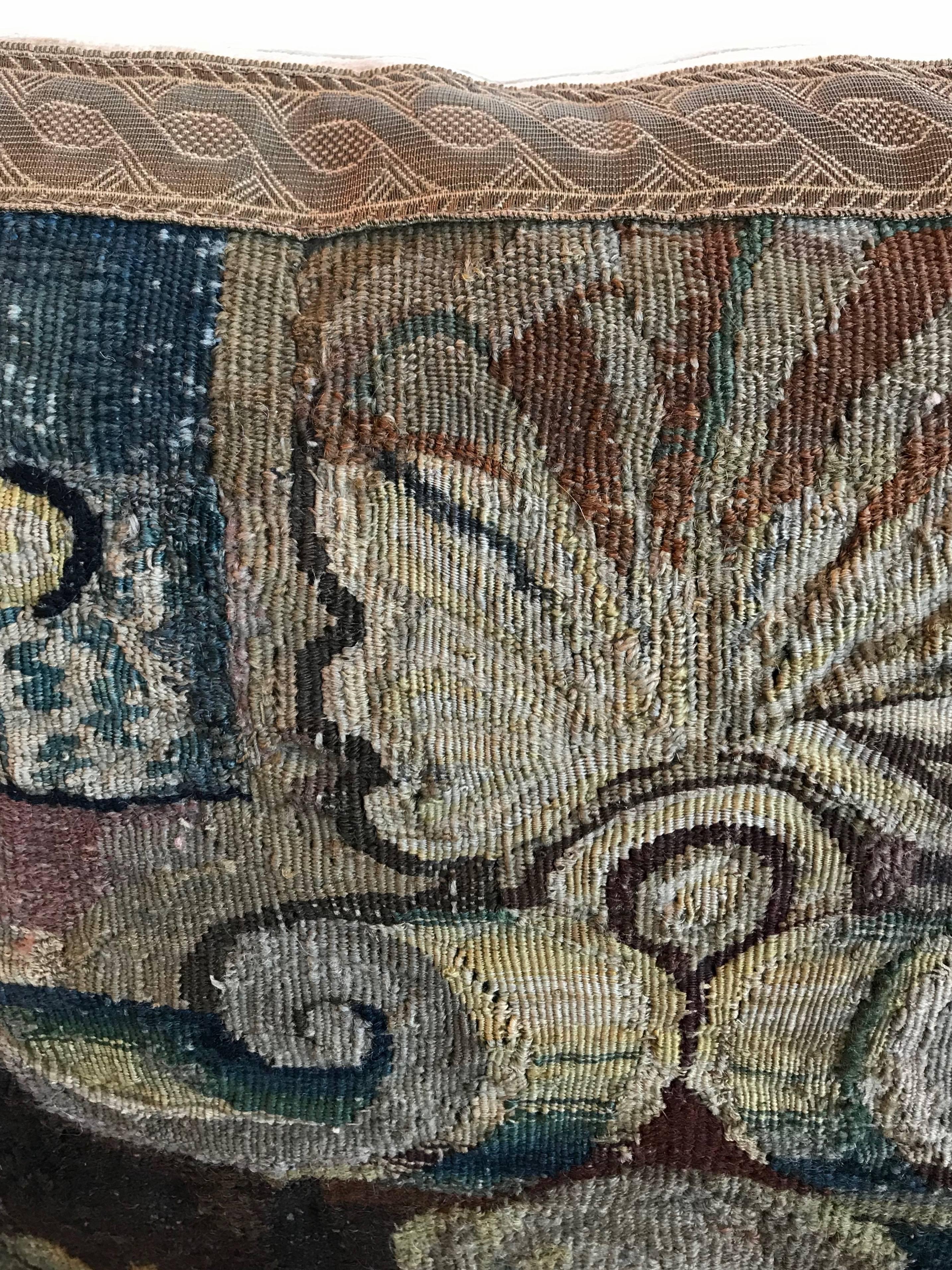 17th century tapestry fragment in shades of taupe, blue, red wine and brown framed with dark gold metallic galon on stone colored velvet. Down-filled.