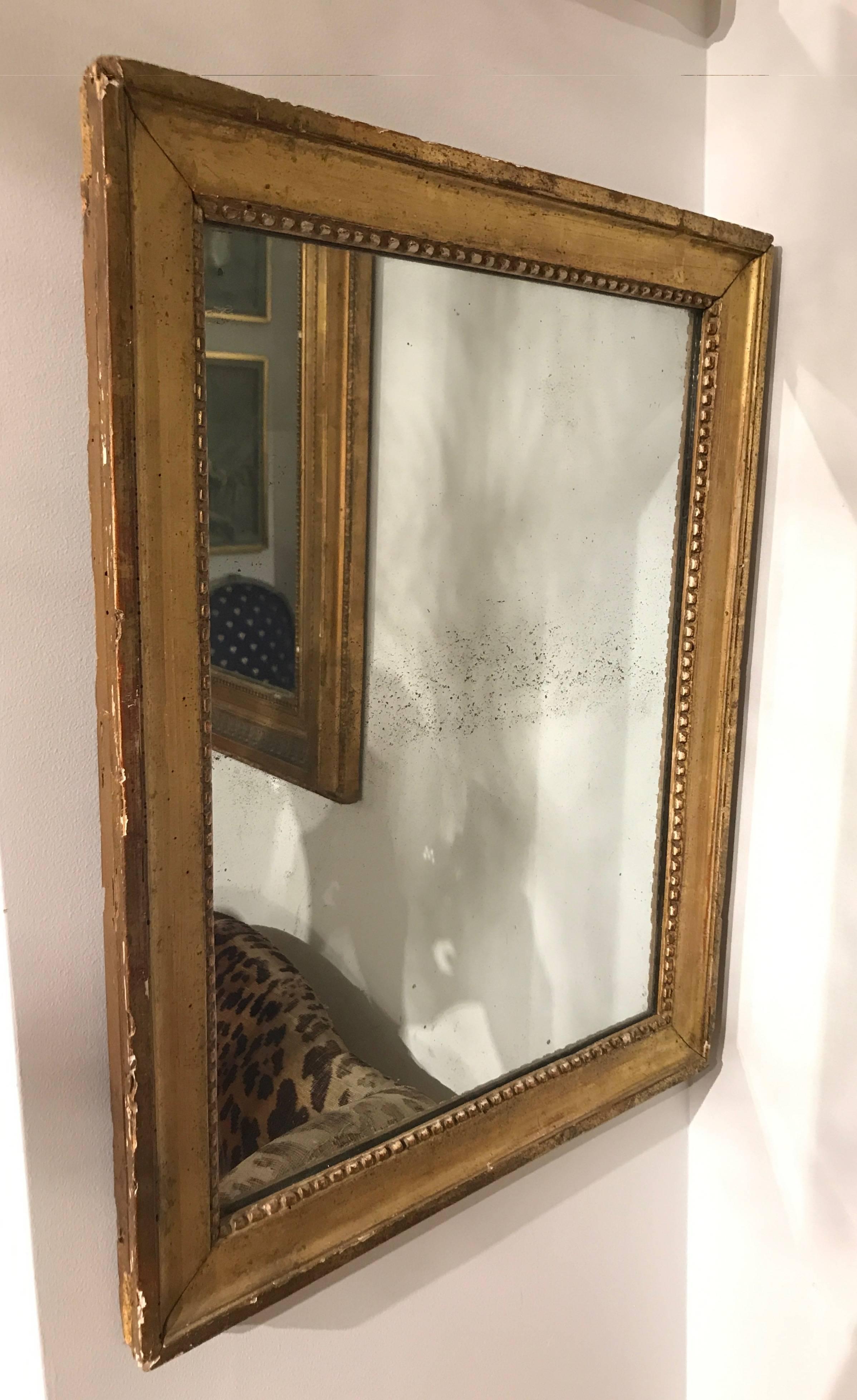 Small-scale giltwood mirror with beaded detailing and original glass.